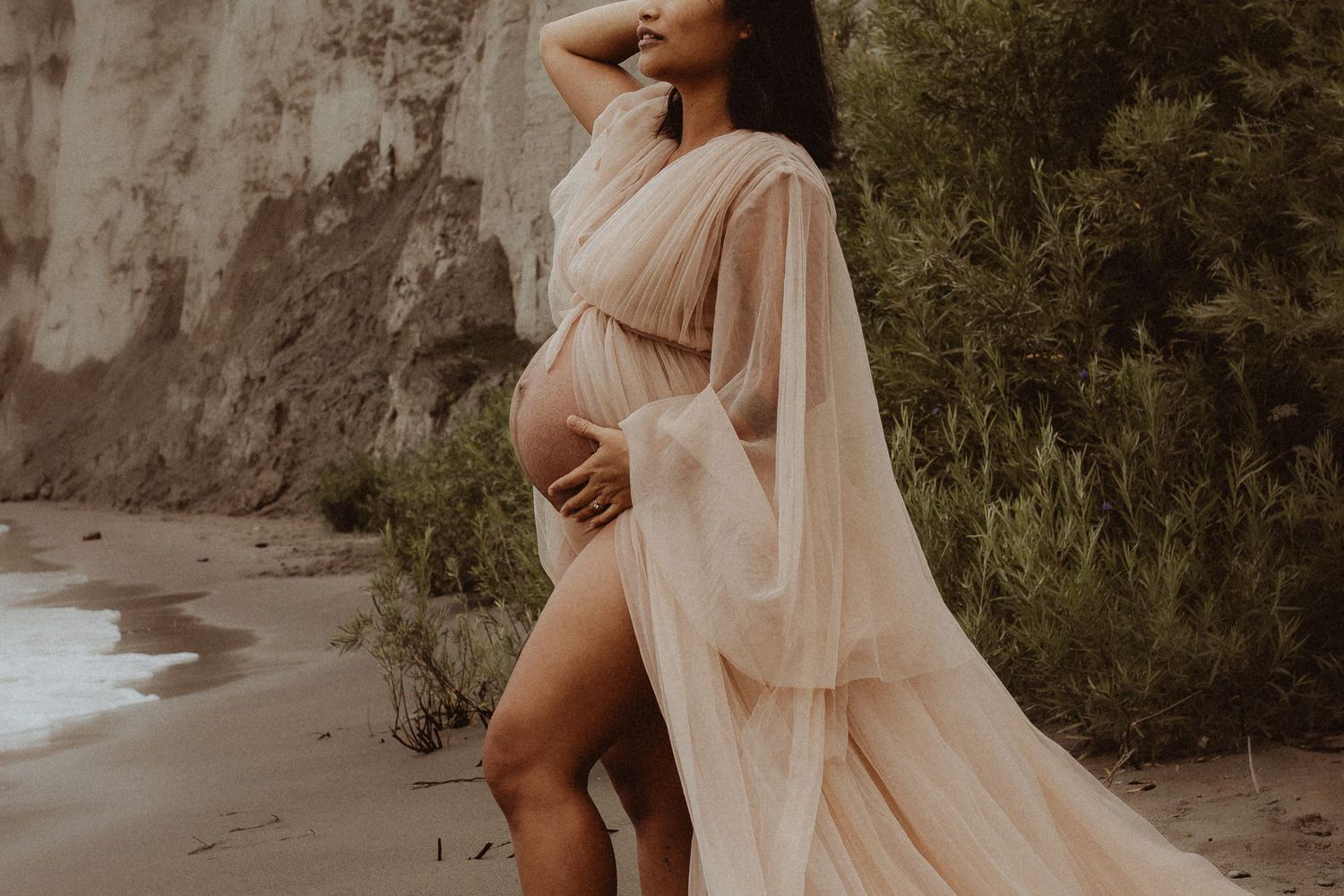 Close-up image of a pregnant mom showing her baby bump in a flowy dress by Durham Region maternity photographer