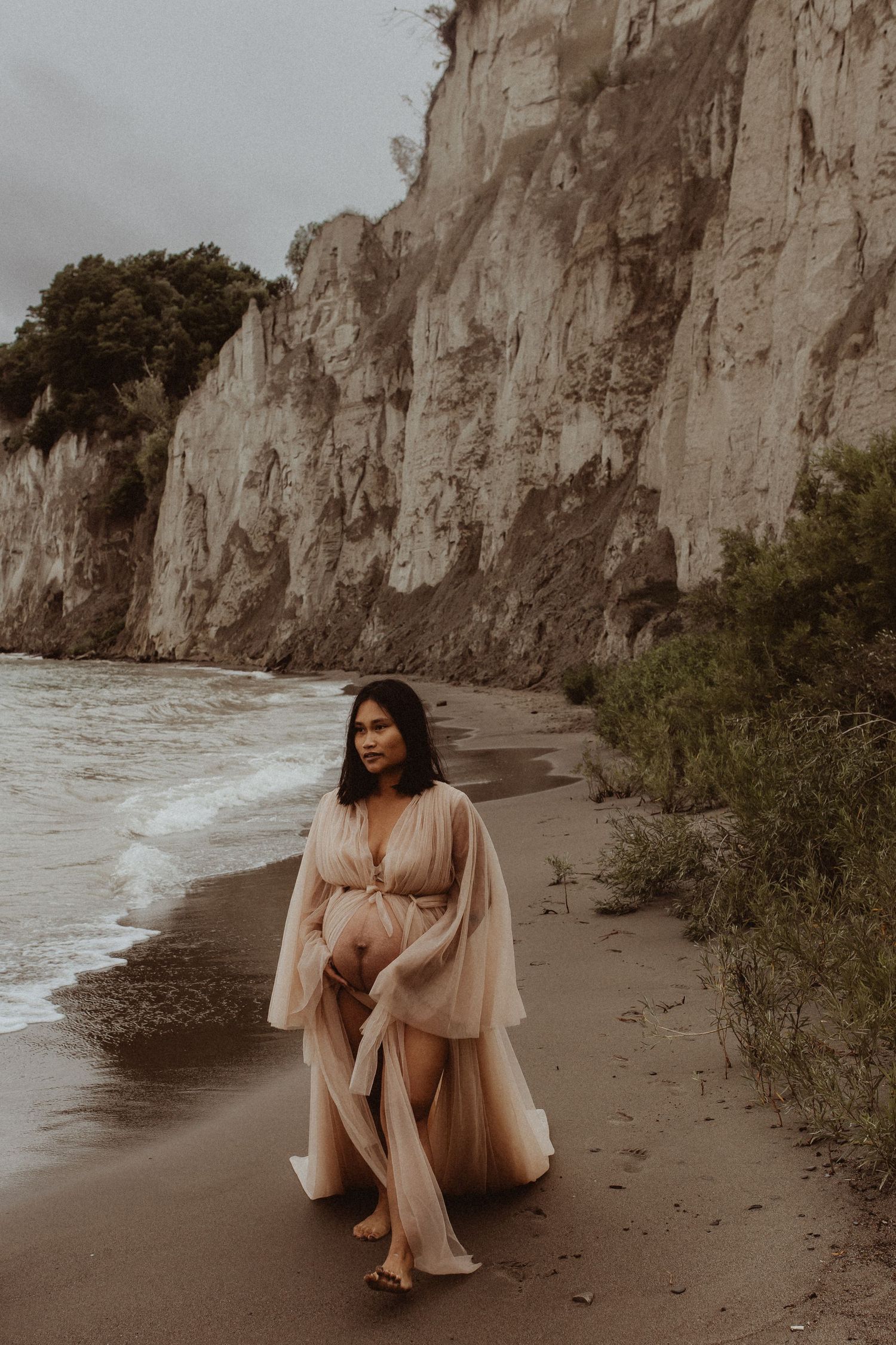 Pregnant woman walking along a beach by Durham Region maternity photographer