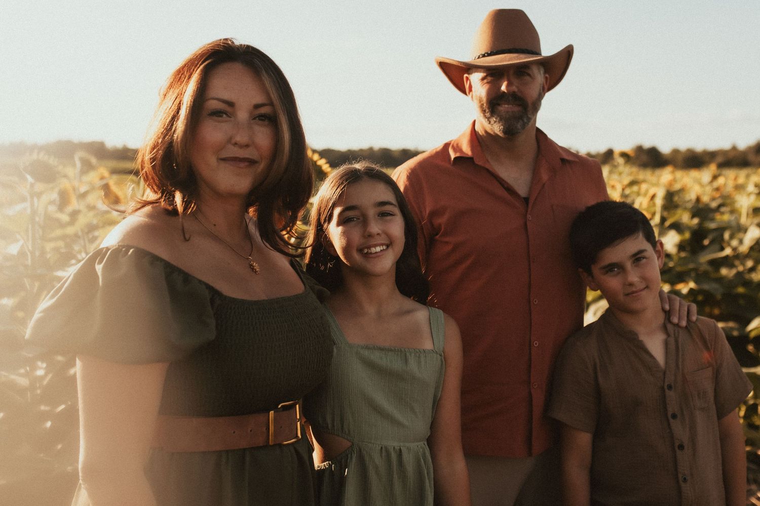A family portrait in the sunflower fields during sunset by Durham Region family photographer