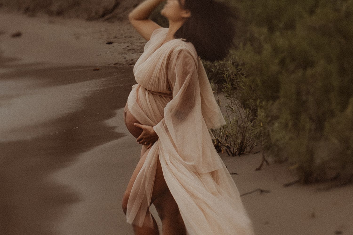 A close-up image of a mom cradling her baby bump in a flowing maternity gown by a Bowmanville maternity photographer.