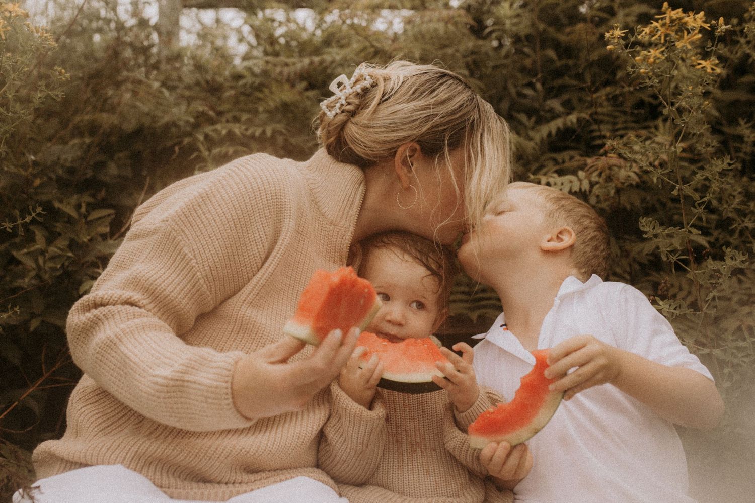 A mom and son share a sweet kiss while they eat watermelon on the beach steps in Cobourg by Cobourg family photographer