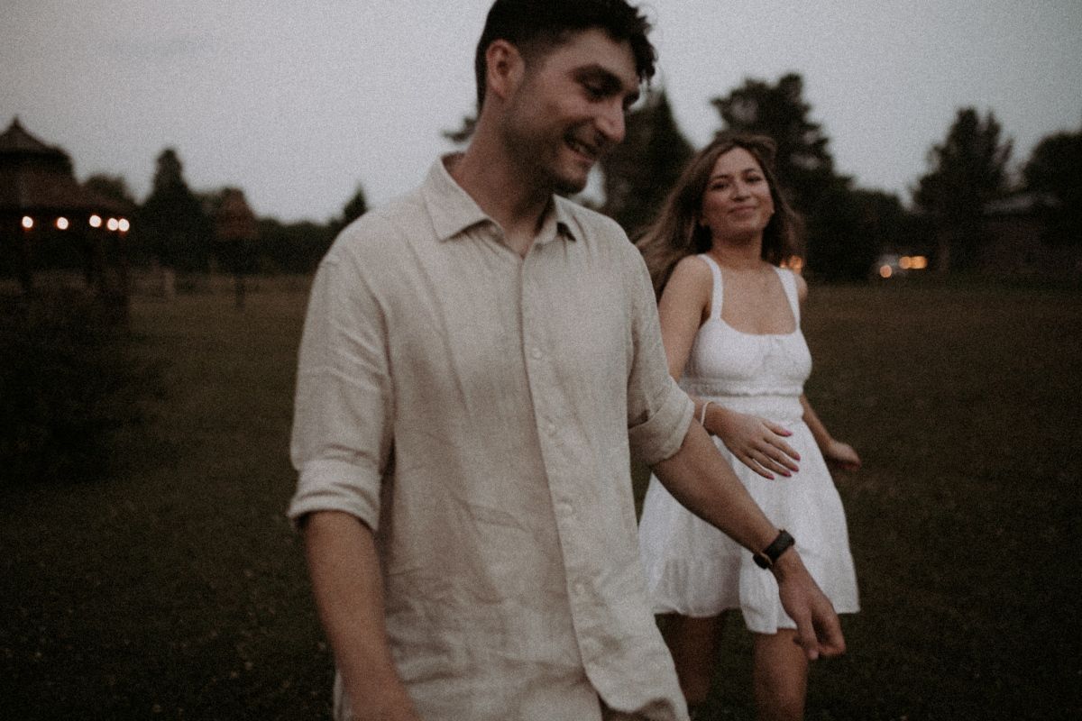 Couple playfully running and chasing each other outdoors, smiling and enjoying a fun, by artistic family photographer Bowmanville, ON.