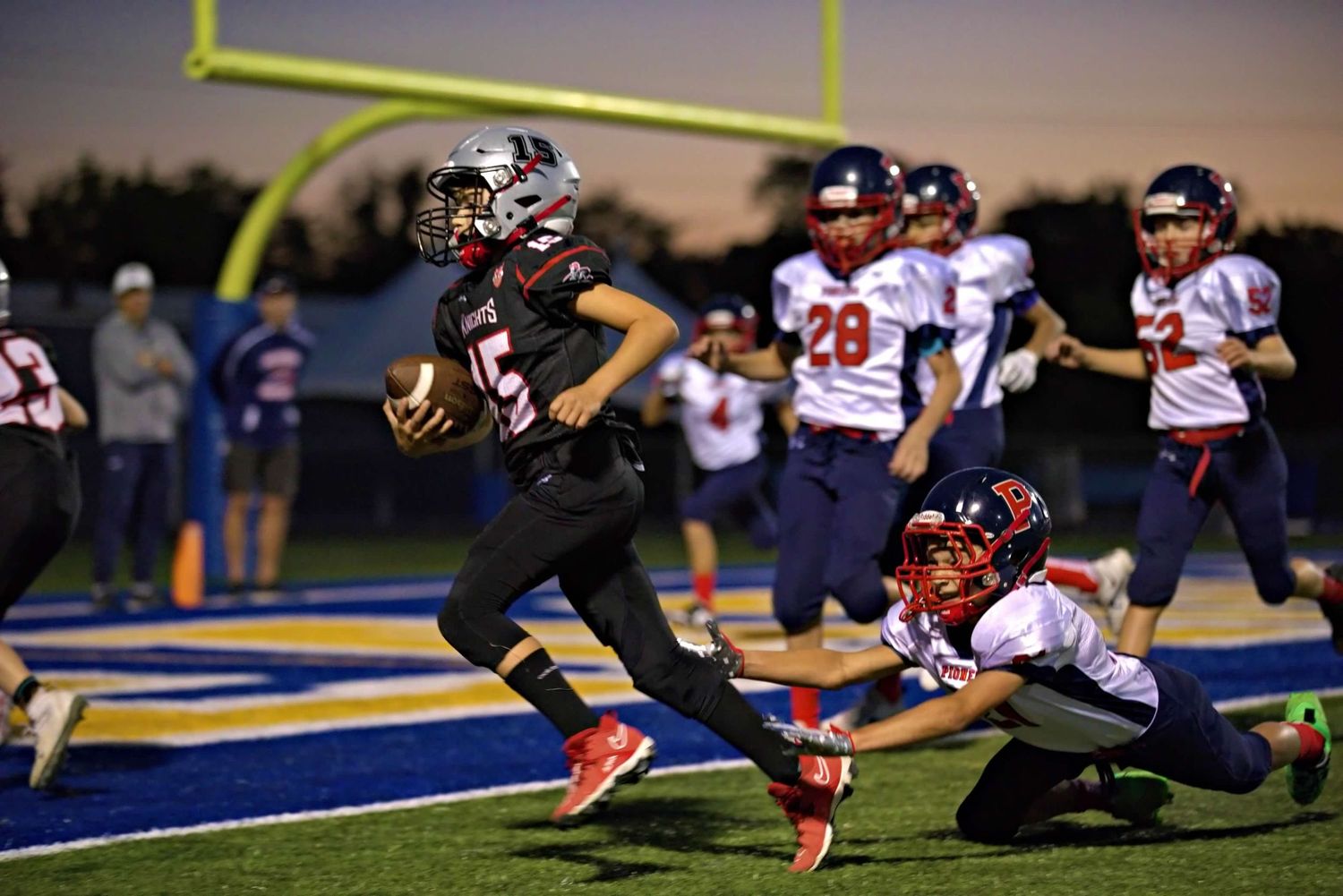 Sequence of action shots showing a football player diving to catch a pass during a night game.