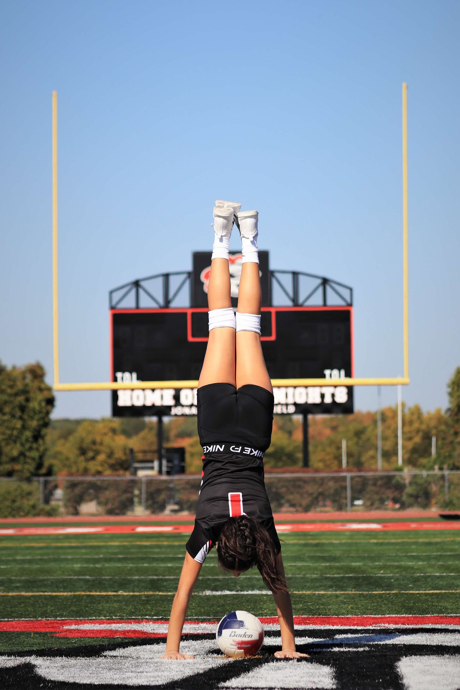 Athletic figure performs handstand sequence on football field showing flexibility and strength against stadium backdrop.