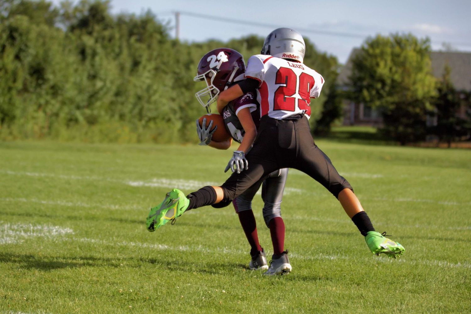 Football players in action on a green field during a practice or training session.