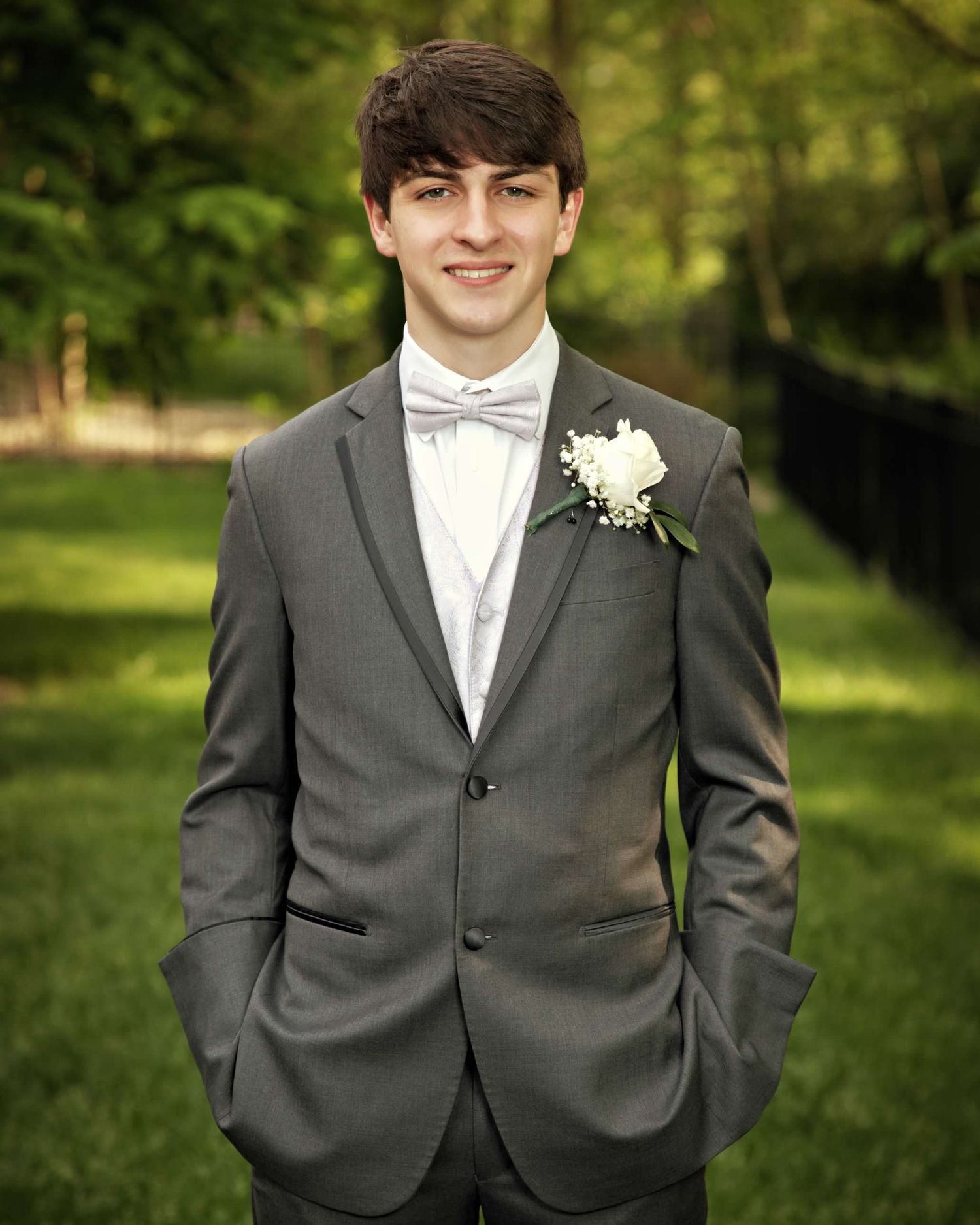 Five connected photos of someone wearing a formal grey suit with white shirt and boutonniere.