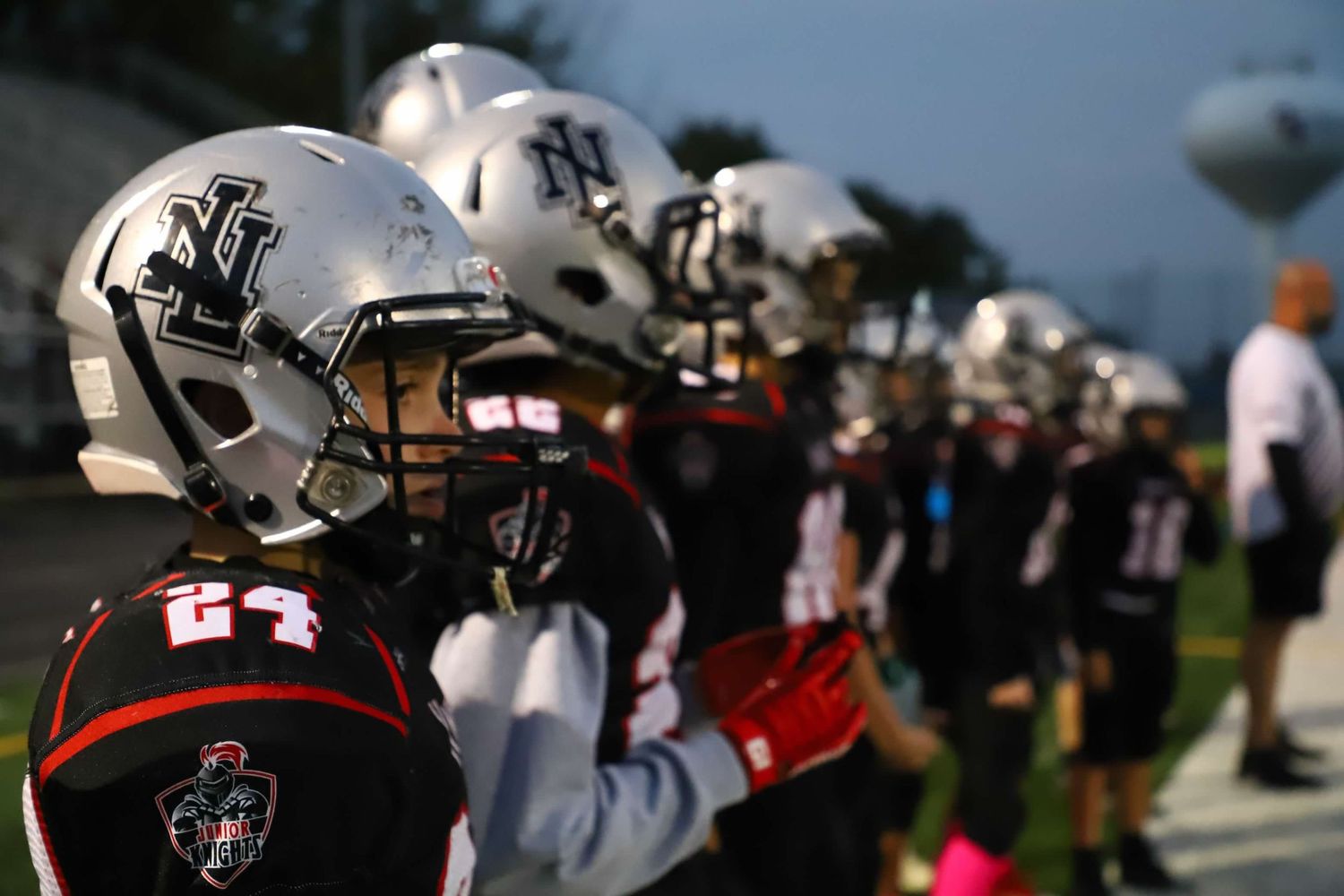 High school football players in uniforms with red and black colors prepare for a play during a game.