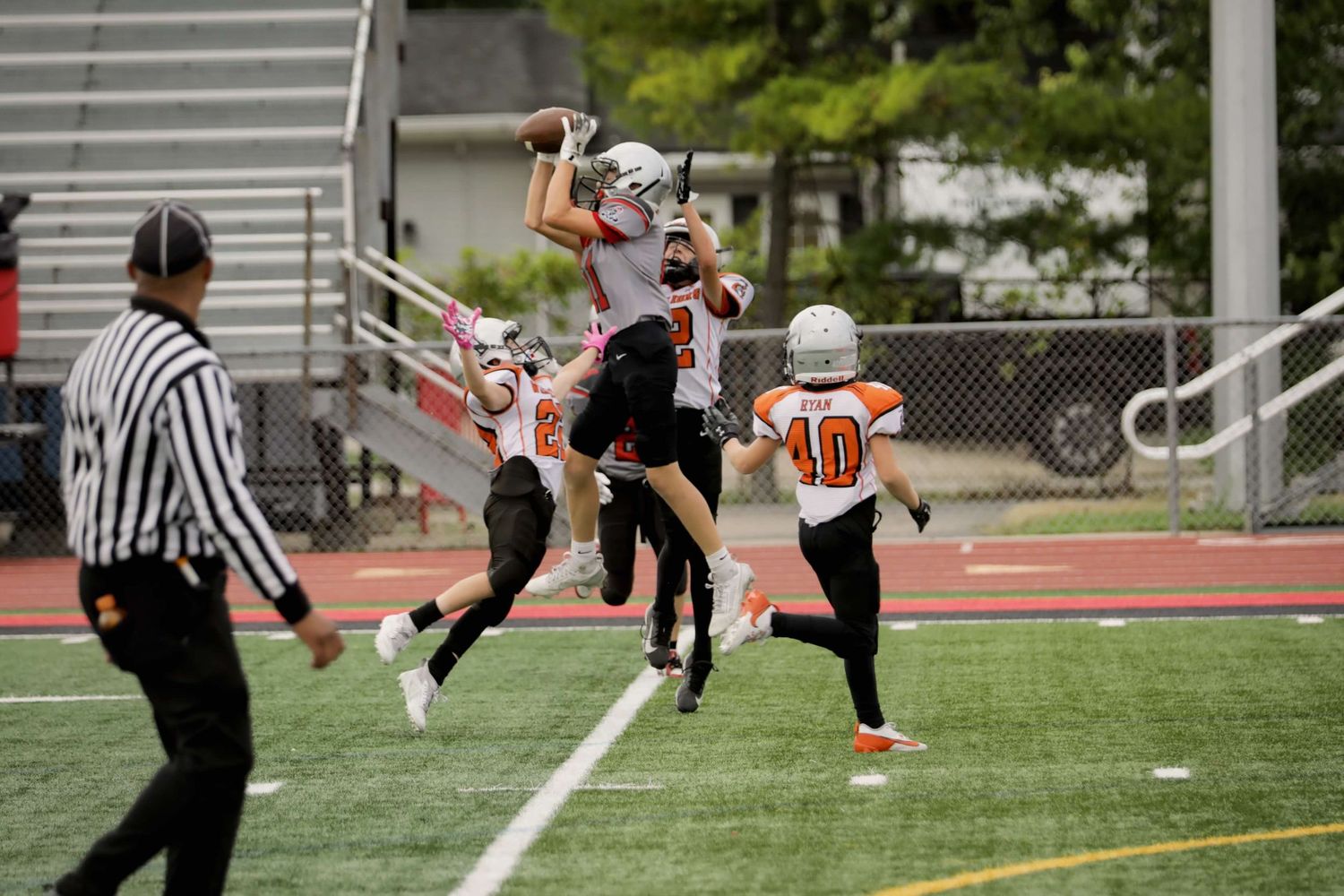 High school football players compete near the goal posts on a green athletic field during an afternoon game.