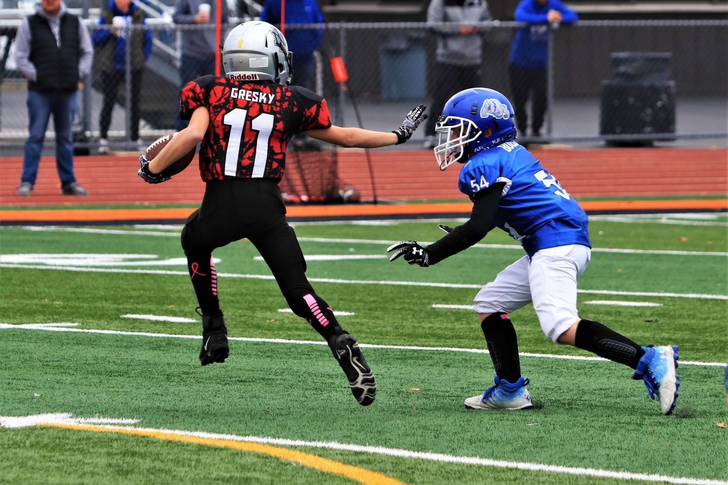 Football players in blue and black jerseys engaged in an intense play on the field.