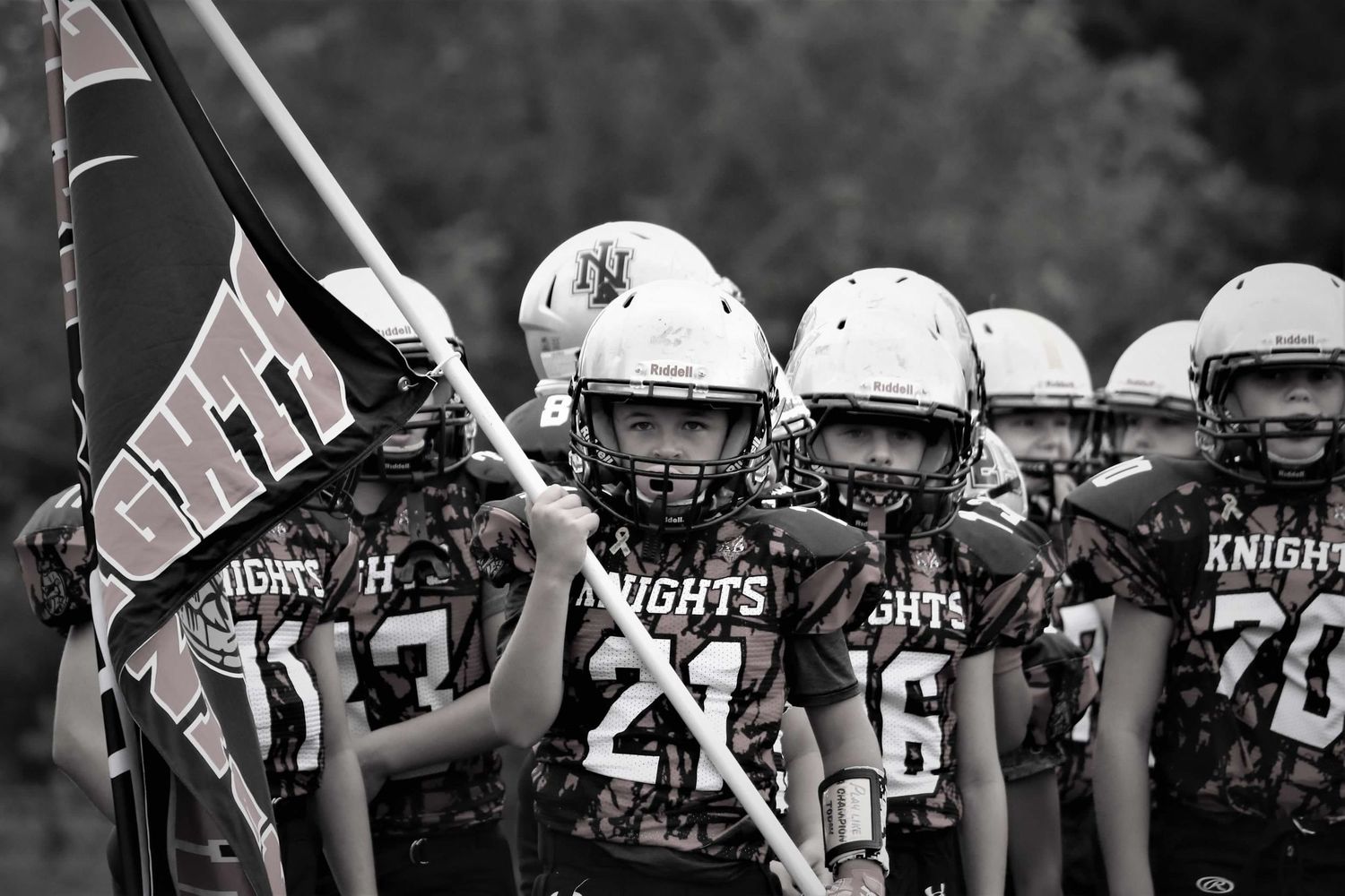 High school football team banners displayed at a sports event in monochrome.