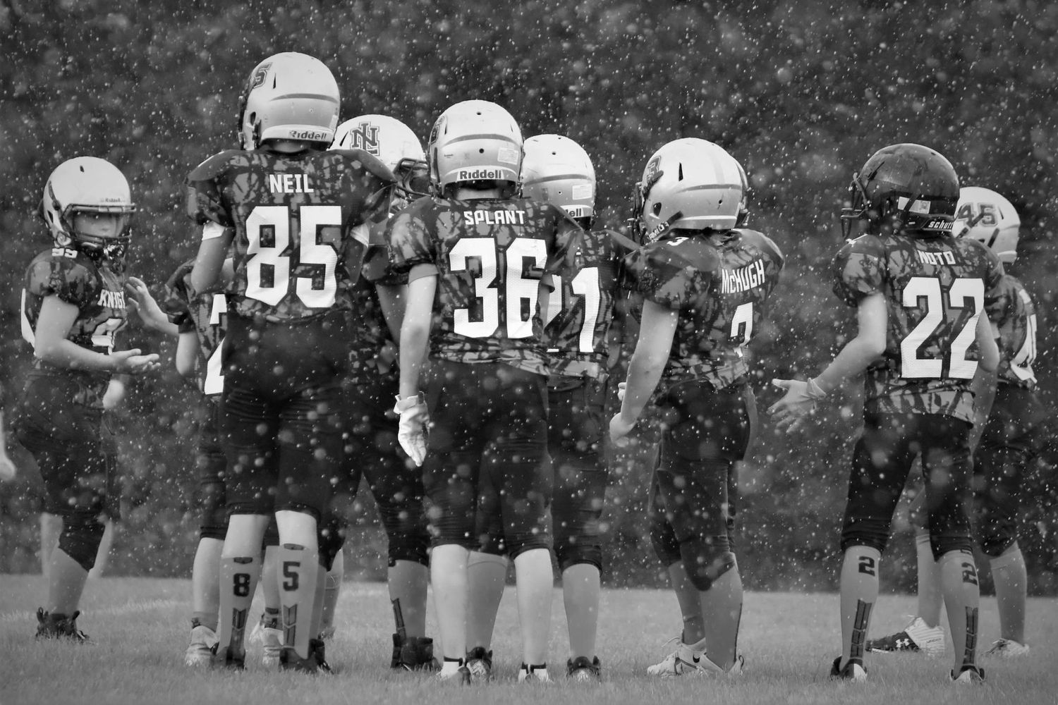 Players wearing football uniforms and helmets stand in formation on a field during a game.