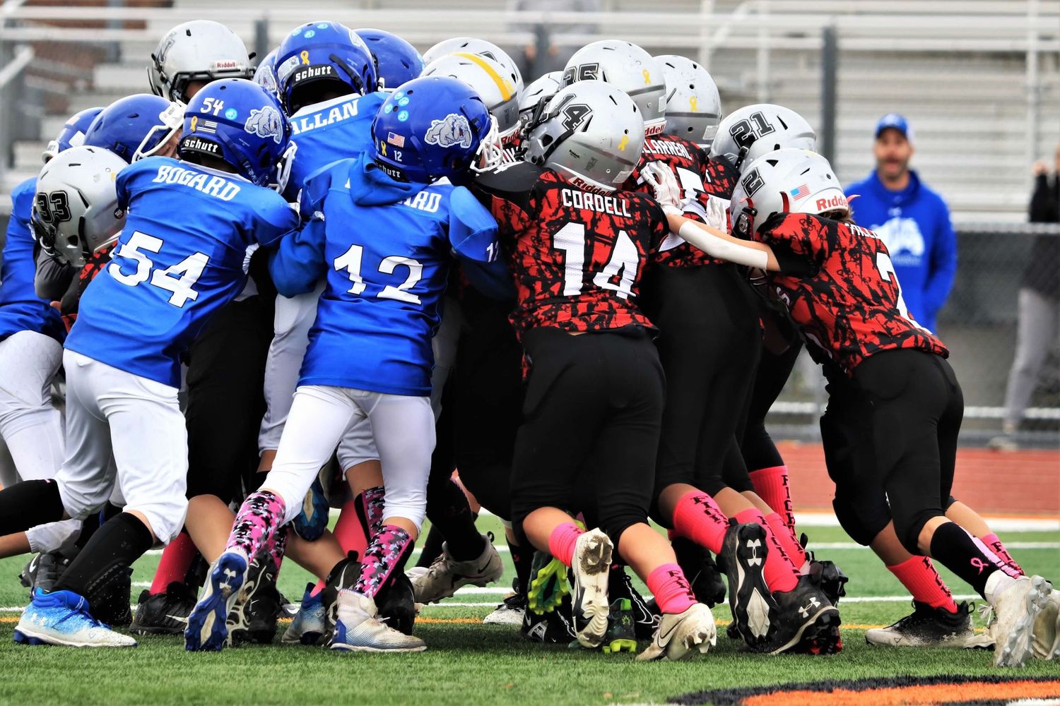 Football players in blue and white uniforms engaged in offensive line formation during game play.