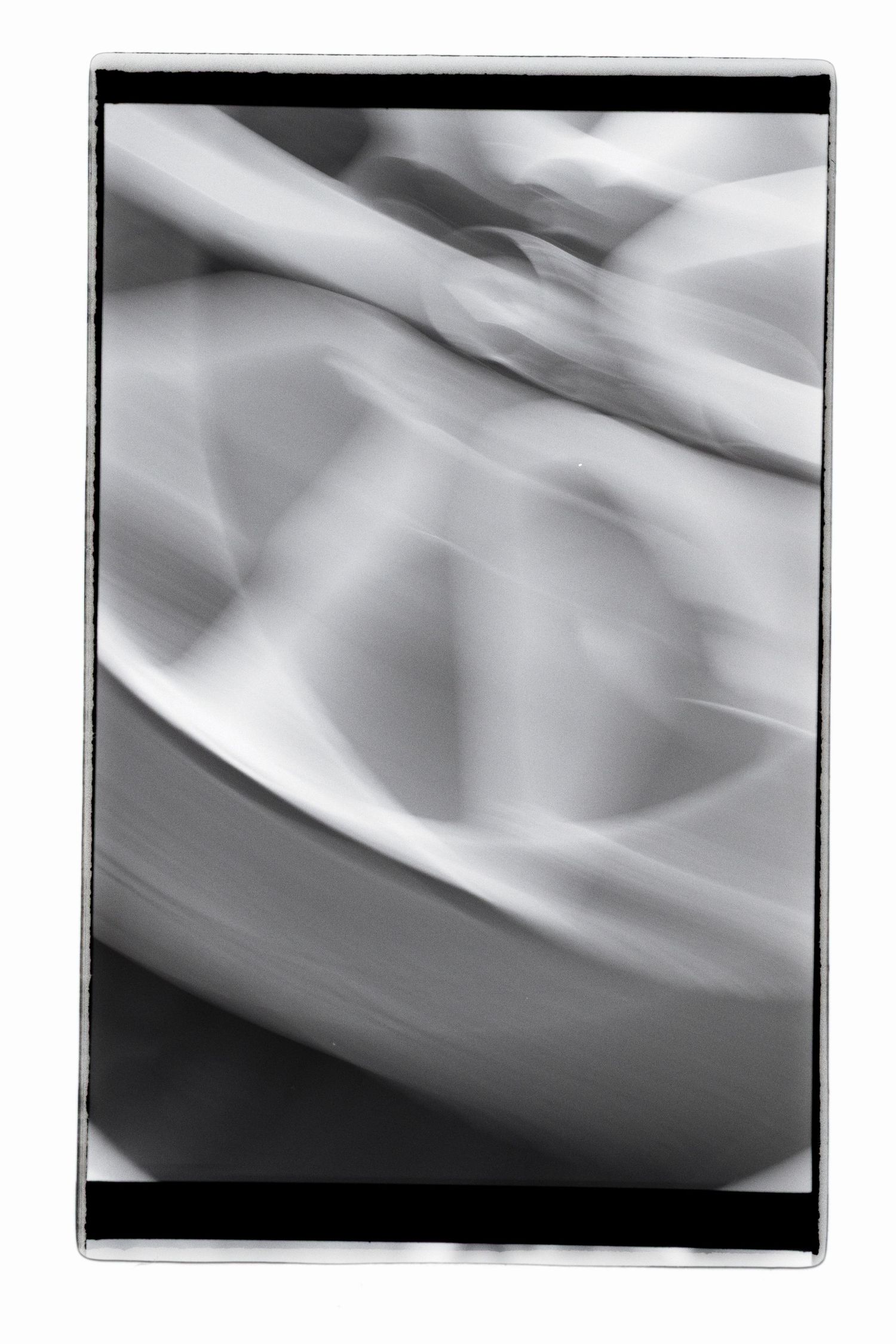 Blurry analog black and white shot with a slow shutter speed of a moving car's wheel.