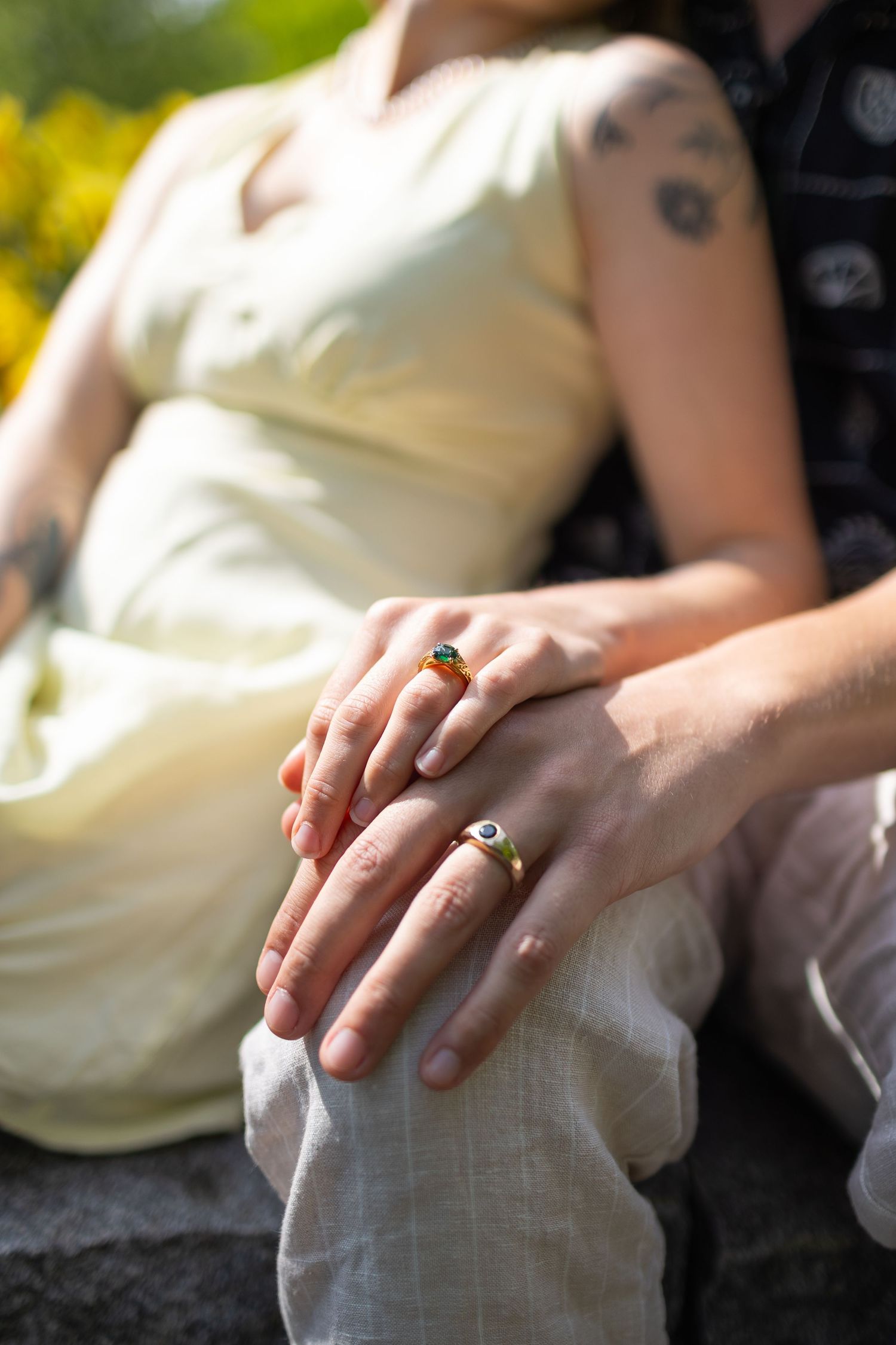 Couple sitting and holding hands, showing off their beautiful engagement rings.