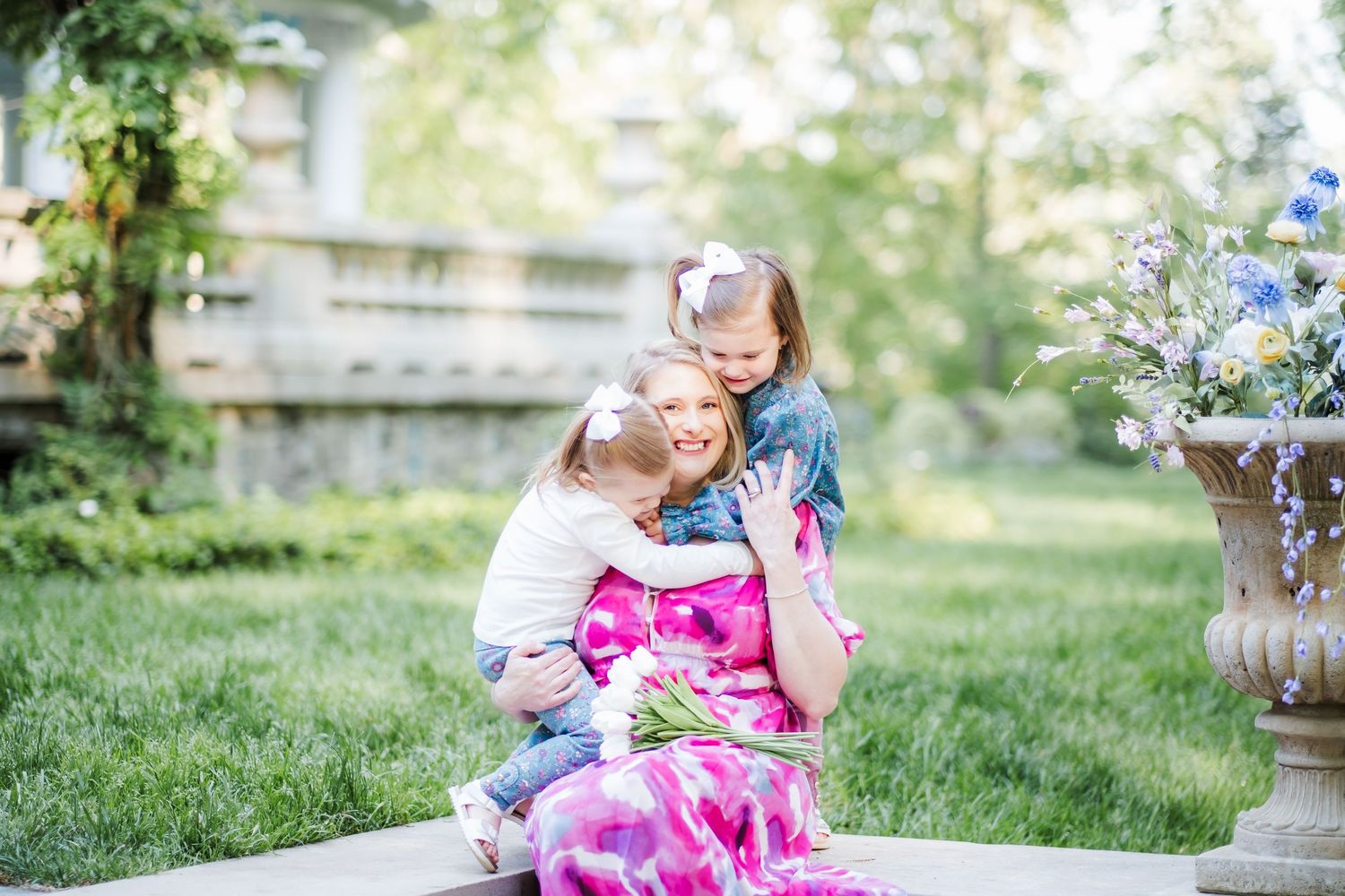 A tender moment shared in a garden setting with pink floral dress and soft natural lighting.
