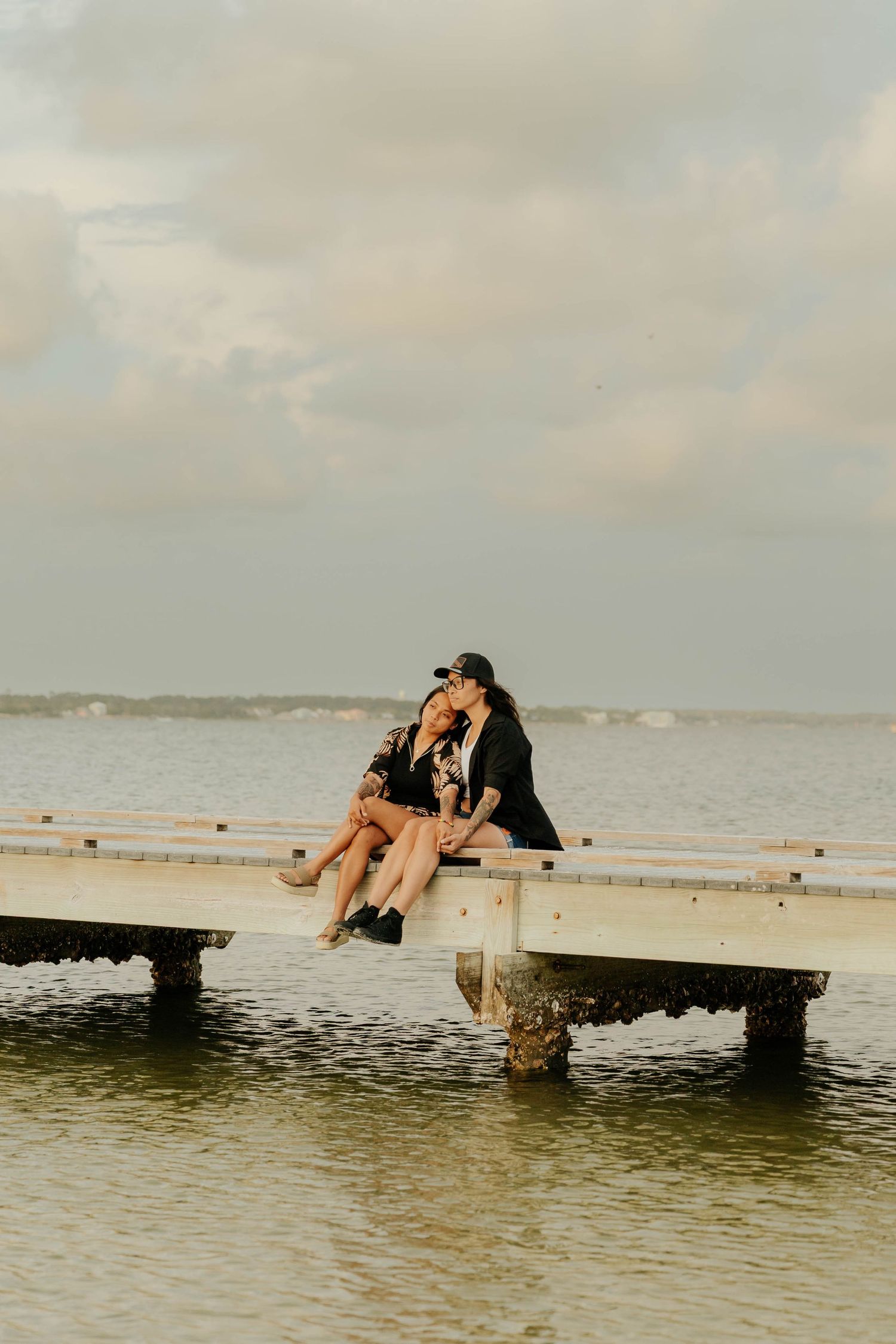 A person lounges on a wooden dock over calm waters at sunset, creating a serene coastal scene.