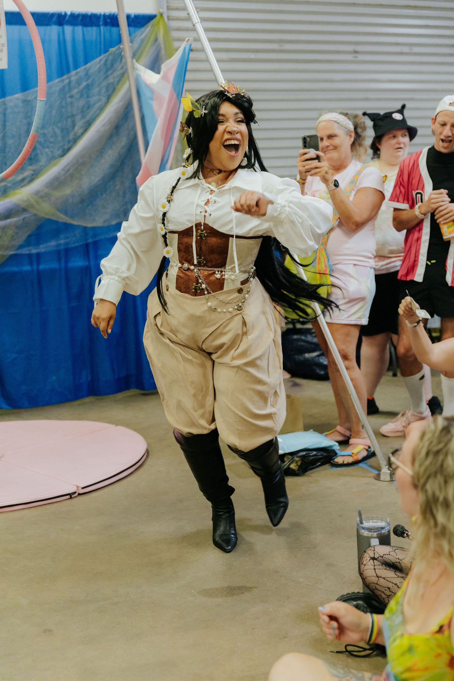 Energetic dancers in beige overalls perform dynamic movements during a lively dance class in a studio space.