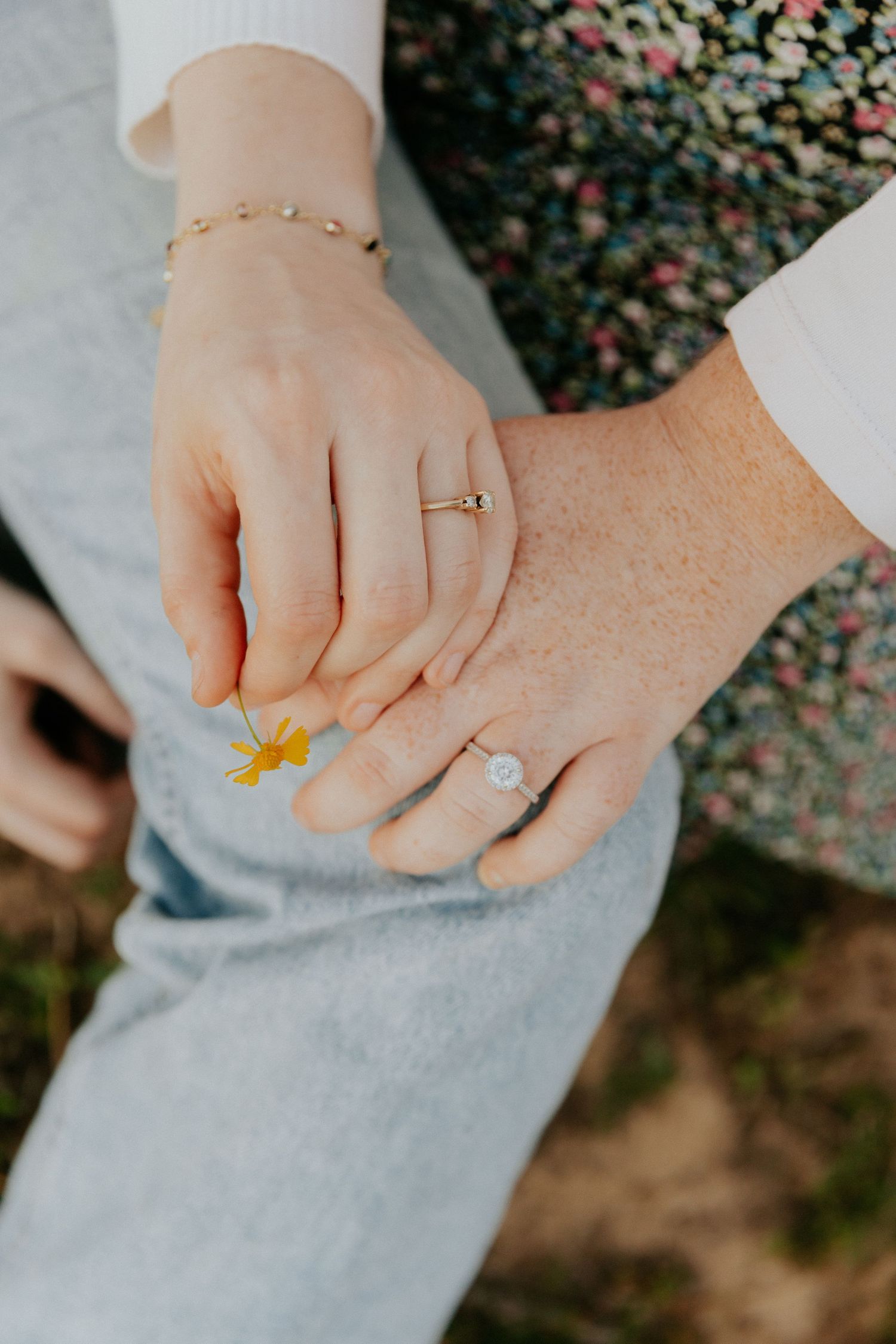 Close-up series of hands holding a delicate yellow wildflower against a soft gray fabric background.