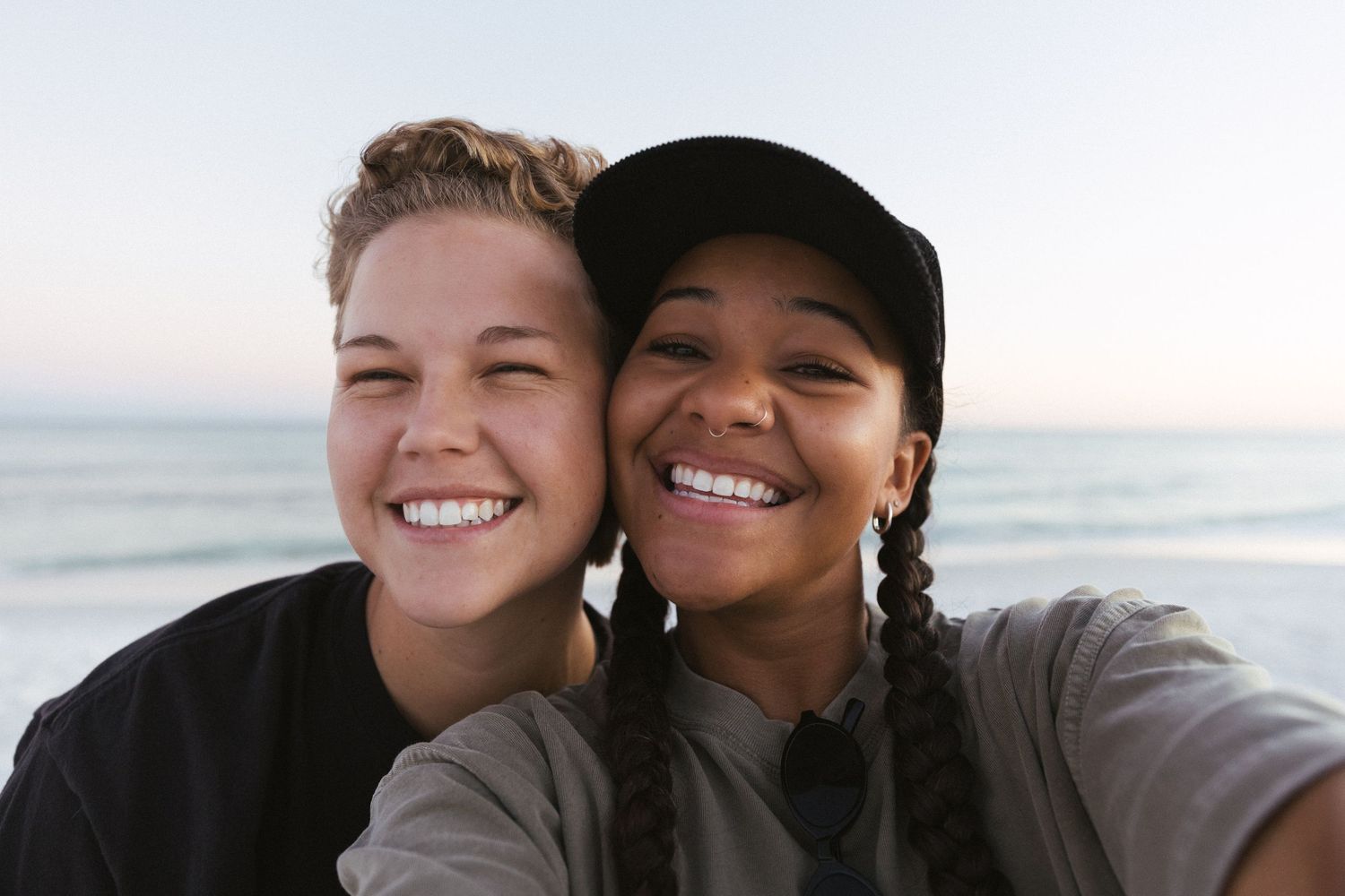 Two people embrace and smile while enjoying a sunset at the beach.