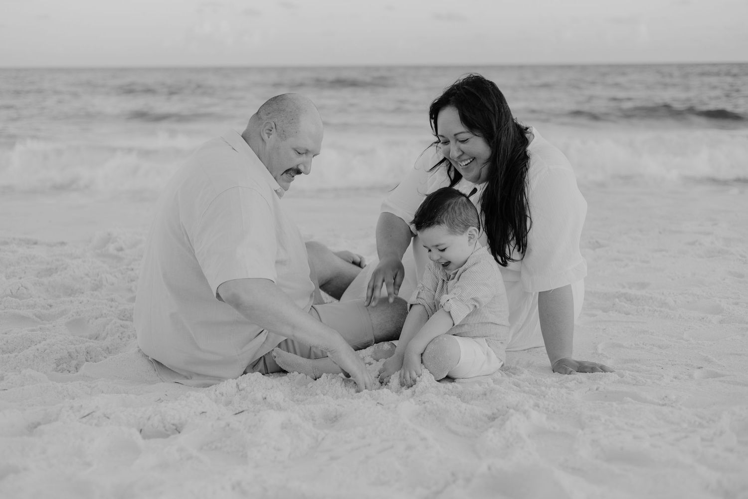 Family photos captured in black and white on a sandy beach.