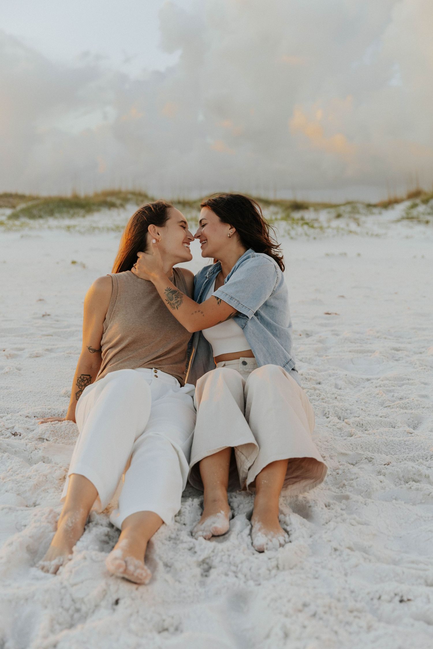 Two people lying close together on pristine white sand beach at dusk.