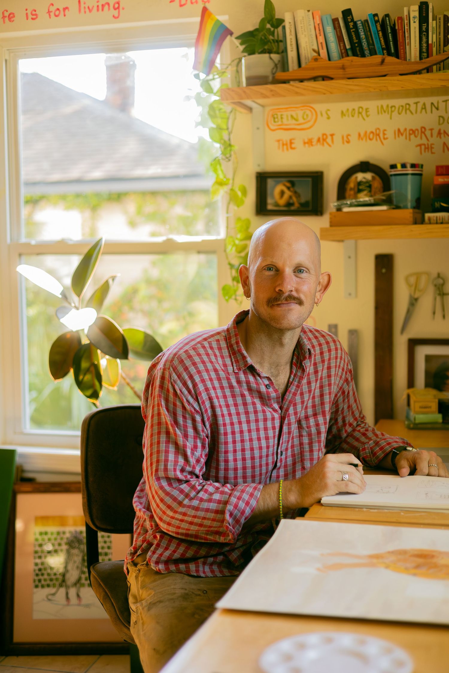 A series of four similar photos showing someone in a red checkered shirt sitting at a desk in a bright office space.