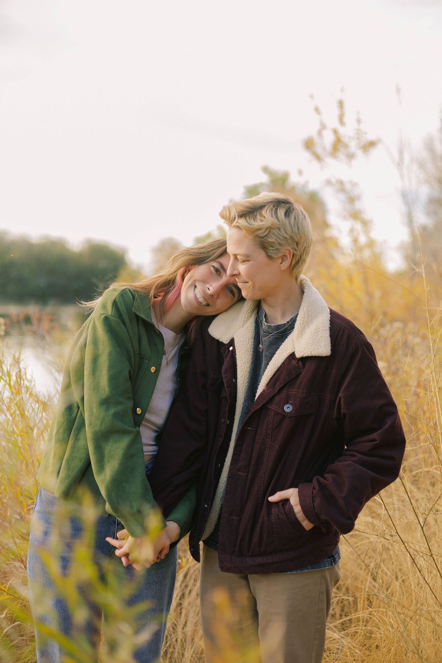 Two people share a tender moment together in a golden autumn field at sunset.