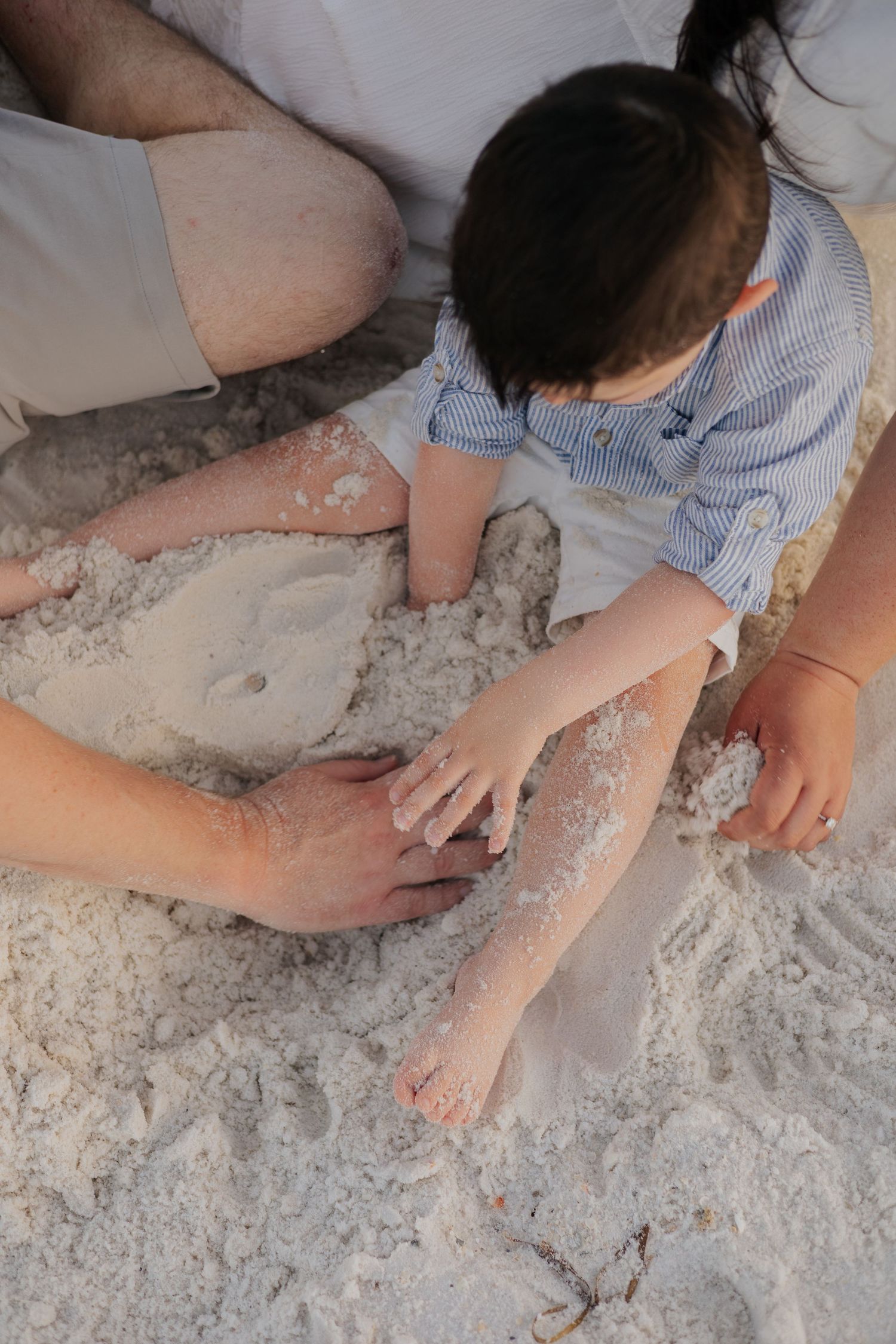 Close-up sequence showing hands playing and making patterns in white sand or flour on a flat surface.