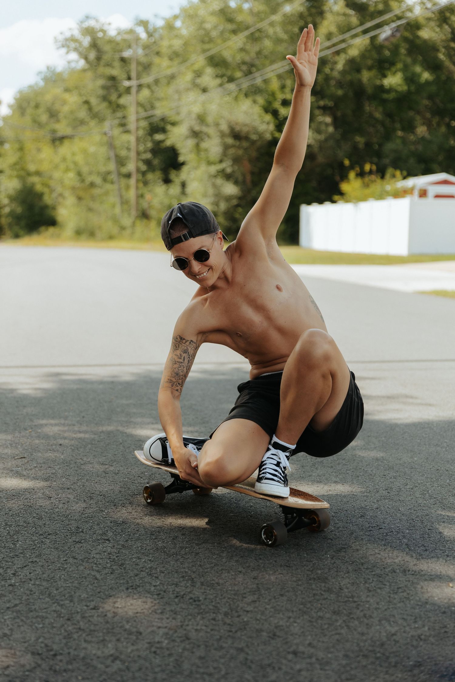 A skateboarder performs a stylish slide maneuver on an empty asphalt road during a sunny day.