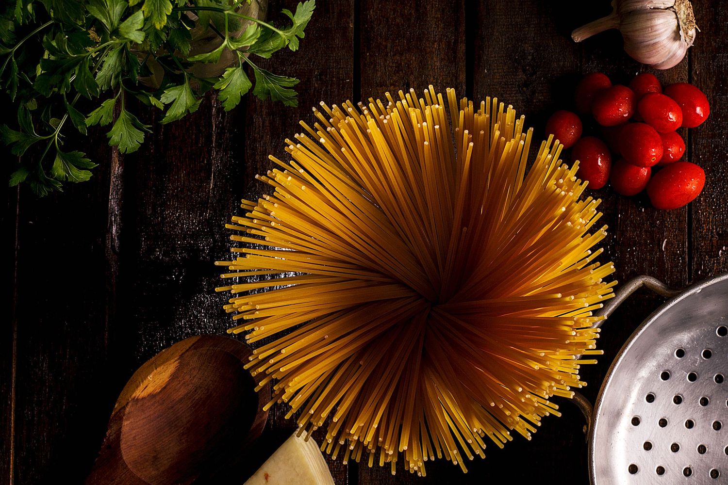 Spaghetti cru em destaque com tomates, alho, queijo e ervas frescas. Tudo pronto para uma receita cheia de sabor e tradição.