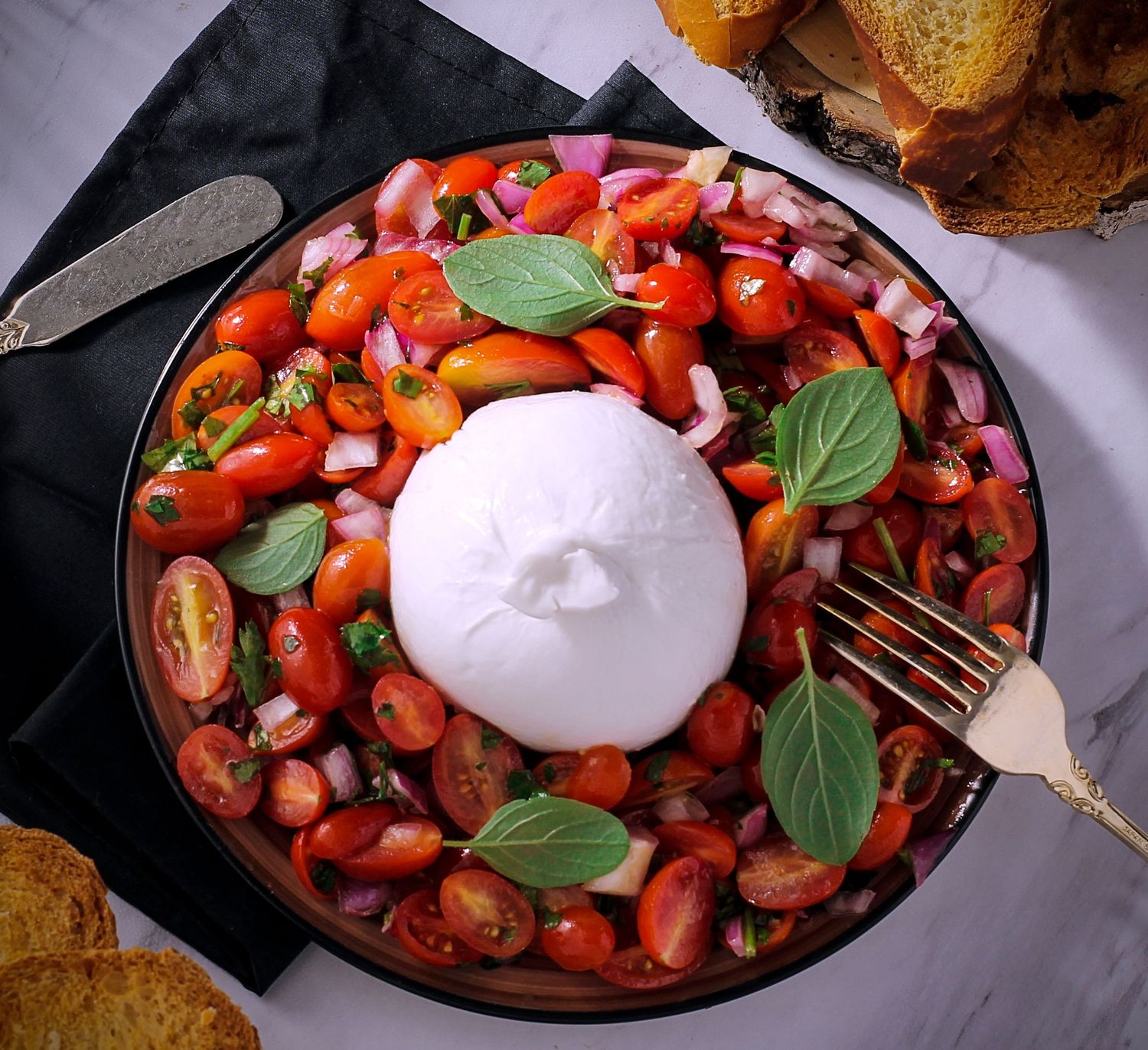 Burrata cremosa com tomates, cebola roxa e manjericão — frescor e cor capturados com elegância e apetite.