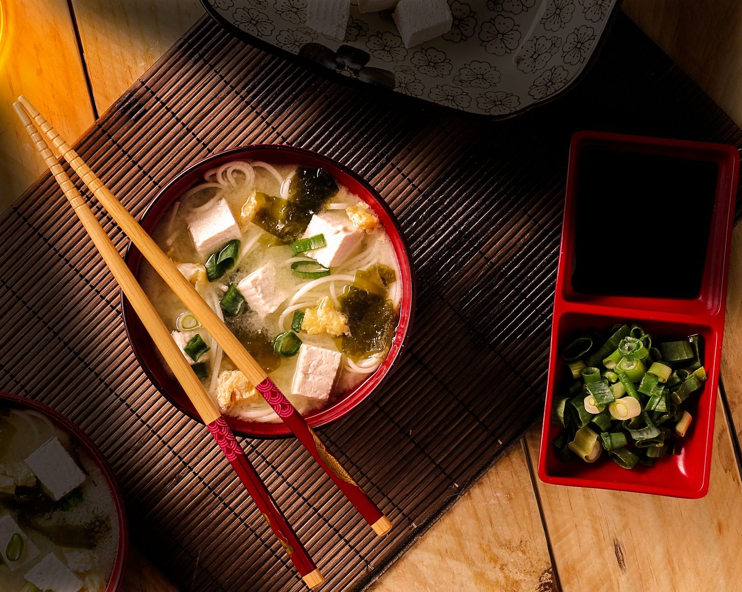 Sopa missoshiro com tofu, algas e cebolinha servida com hashis. Tradição japonesa em uma composição delicada e acolhedora.