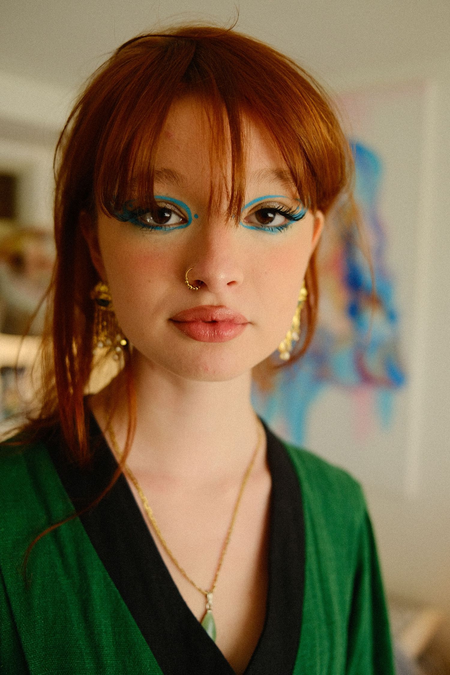 portrait d'une femme rousse, maquillée avec des eye liners bleu sur les yeux. maquillage audacieux qui la met en valeur. visage naturel