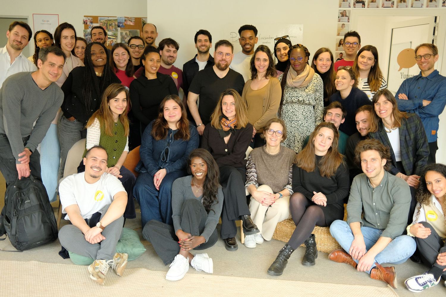 groupe de collègue après une conférence, tous sourient, certains sont par terre d'autres debout, ambiance joviale