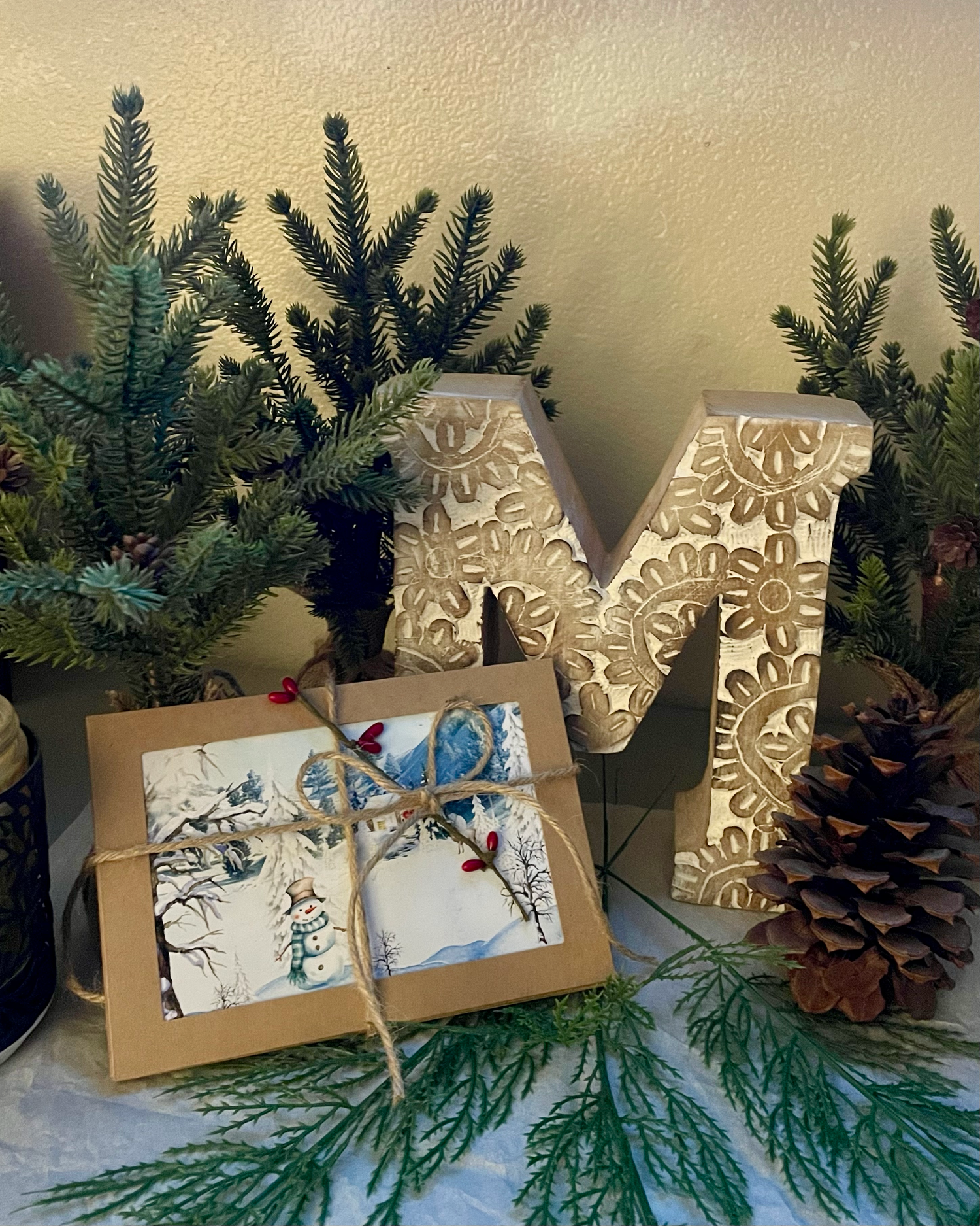 example pack of five Christmas of cards with decorative M letter, pine branches, pinecone, and wrapped cards with brown ribbon bow.