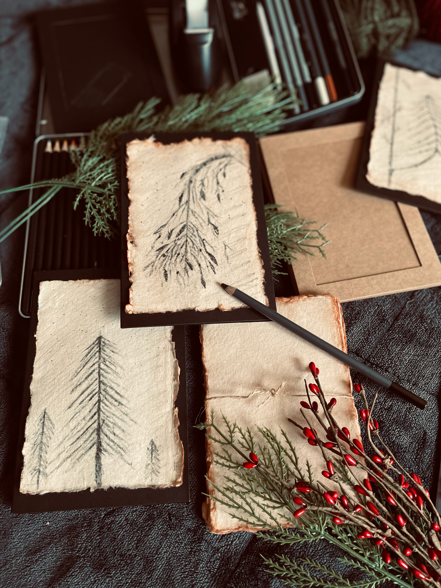 Hand-drawn pine tree sketches on aged paper with red berries and cedar branches holiday art display. Available to purchase. Each is unique.