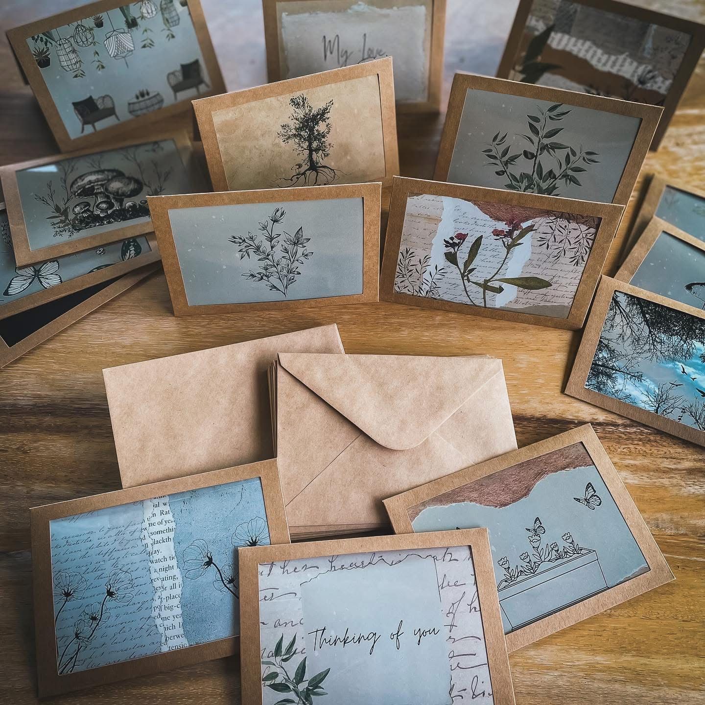 Collection of botanical greeting cards with kraft paper envelopes arranged on a wooden table.