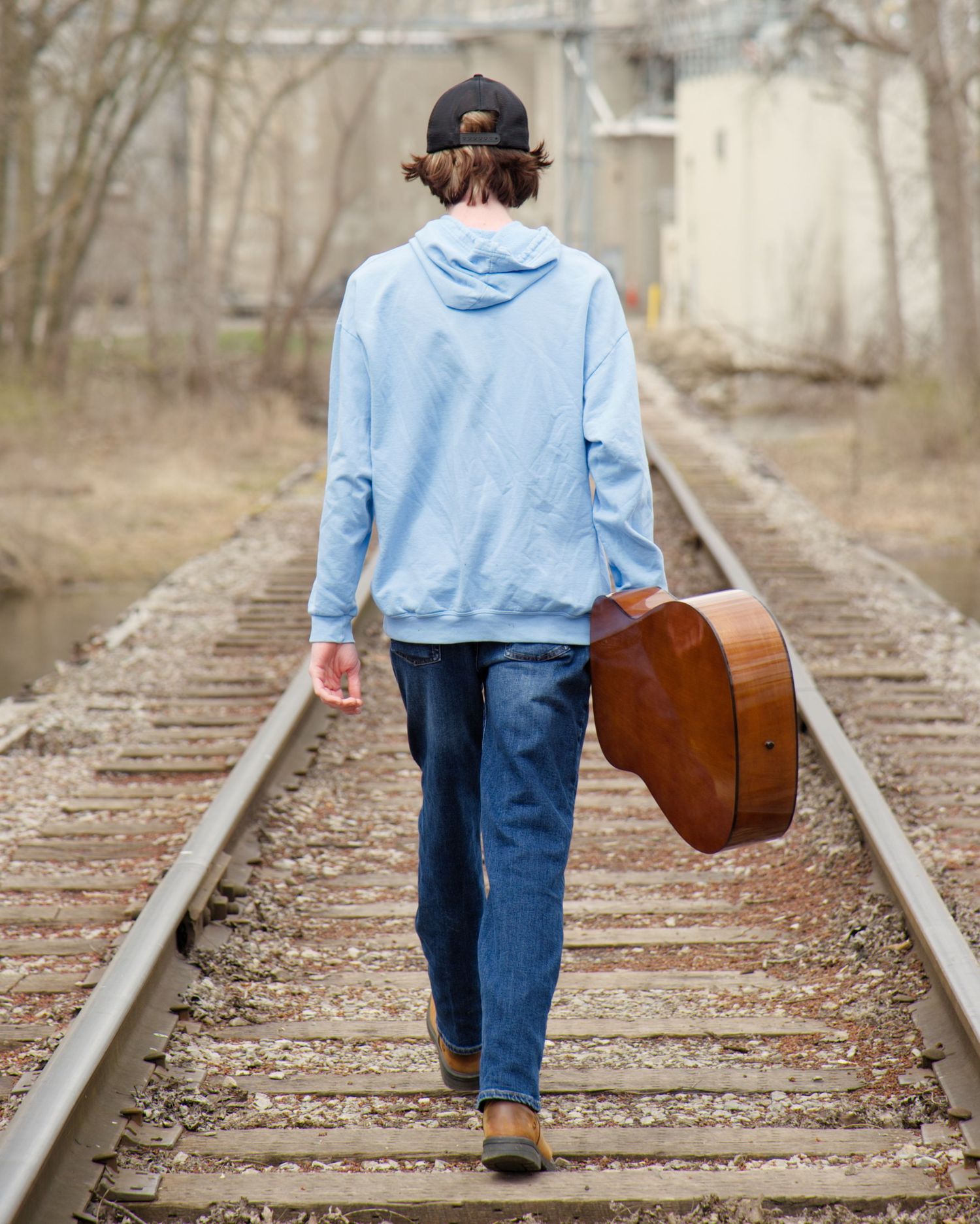 boy walking away with guitar