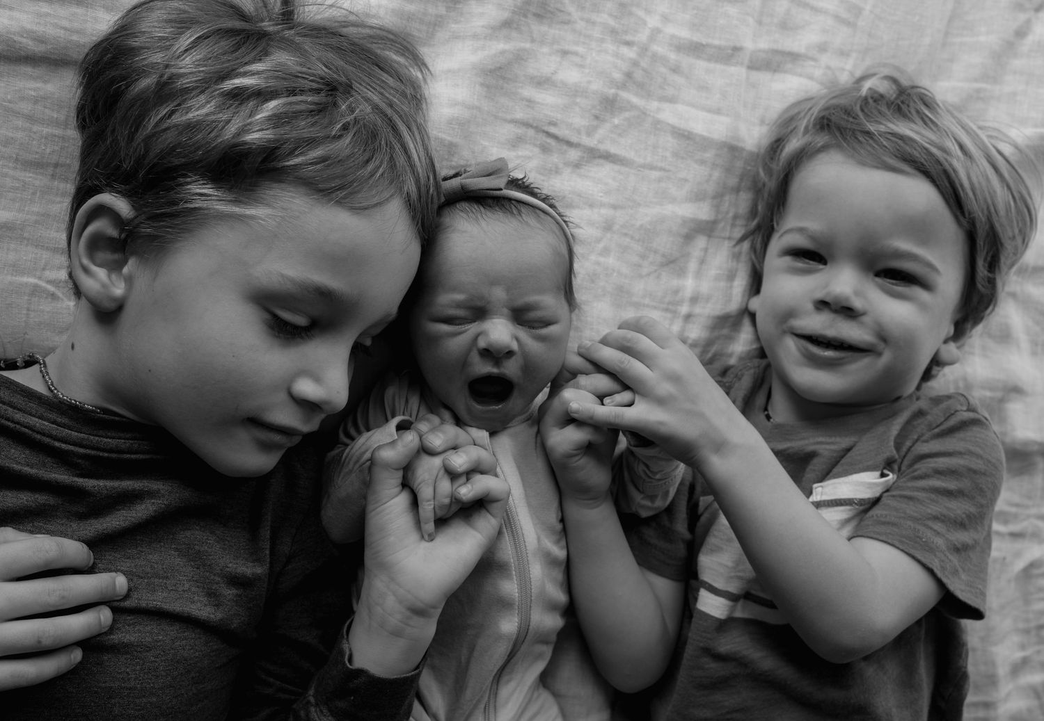 Black and white sequence of children playing and laughing together on fabric.
