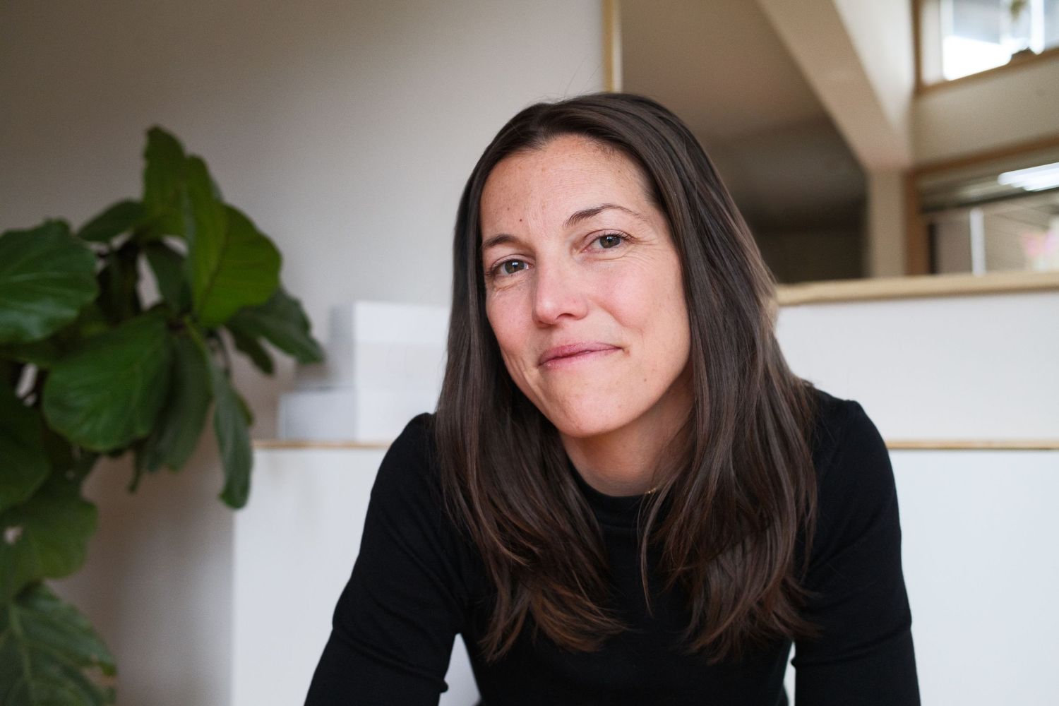 Woman sitting in modern interior with natural lighting.