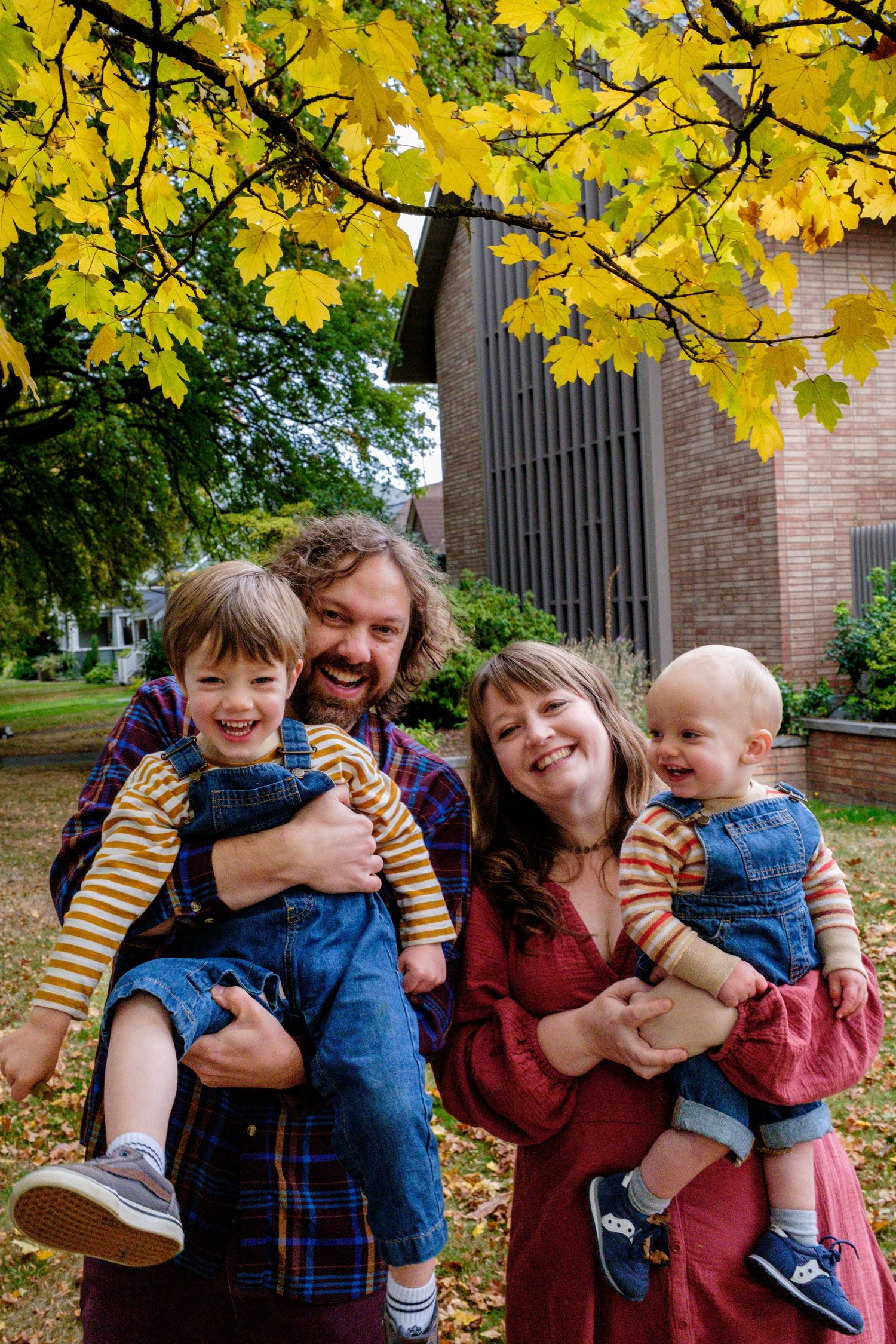 A playful autumn photoshoot under yellow leaves with people laughing and hugging.