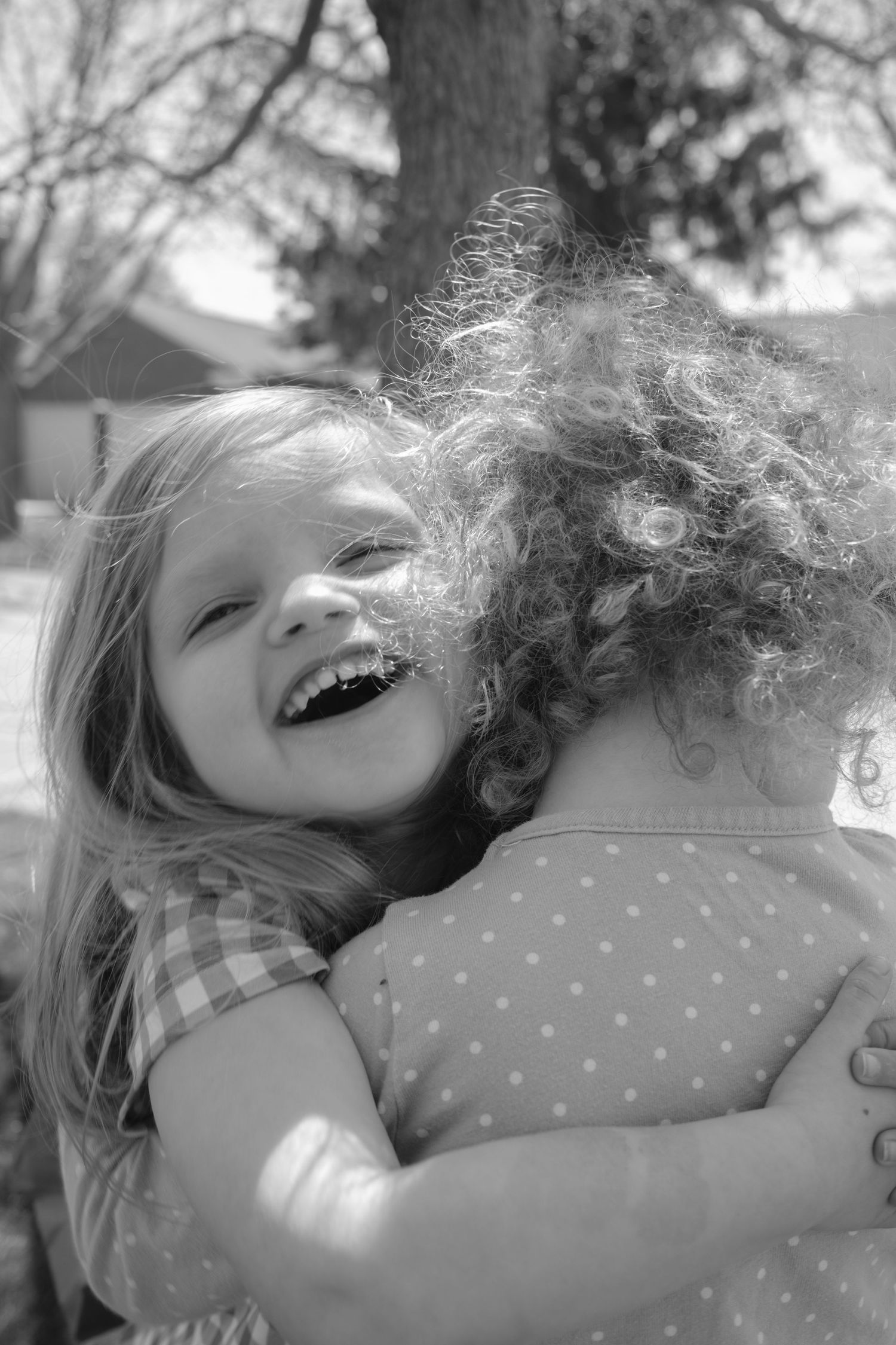 Black and white image shows child laying on pillow with windswept hair.
