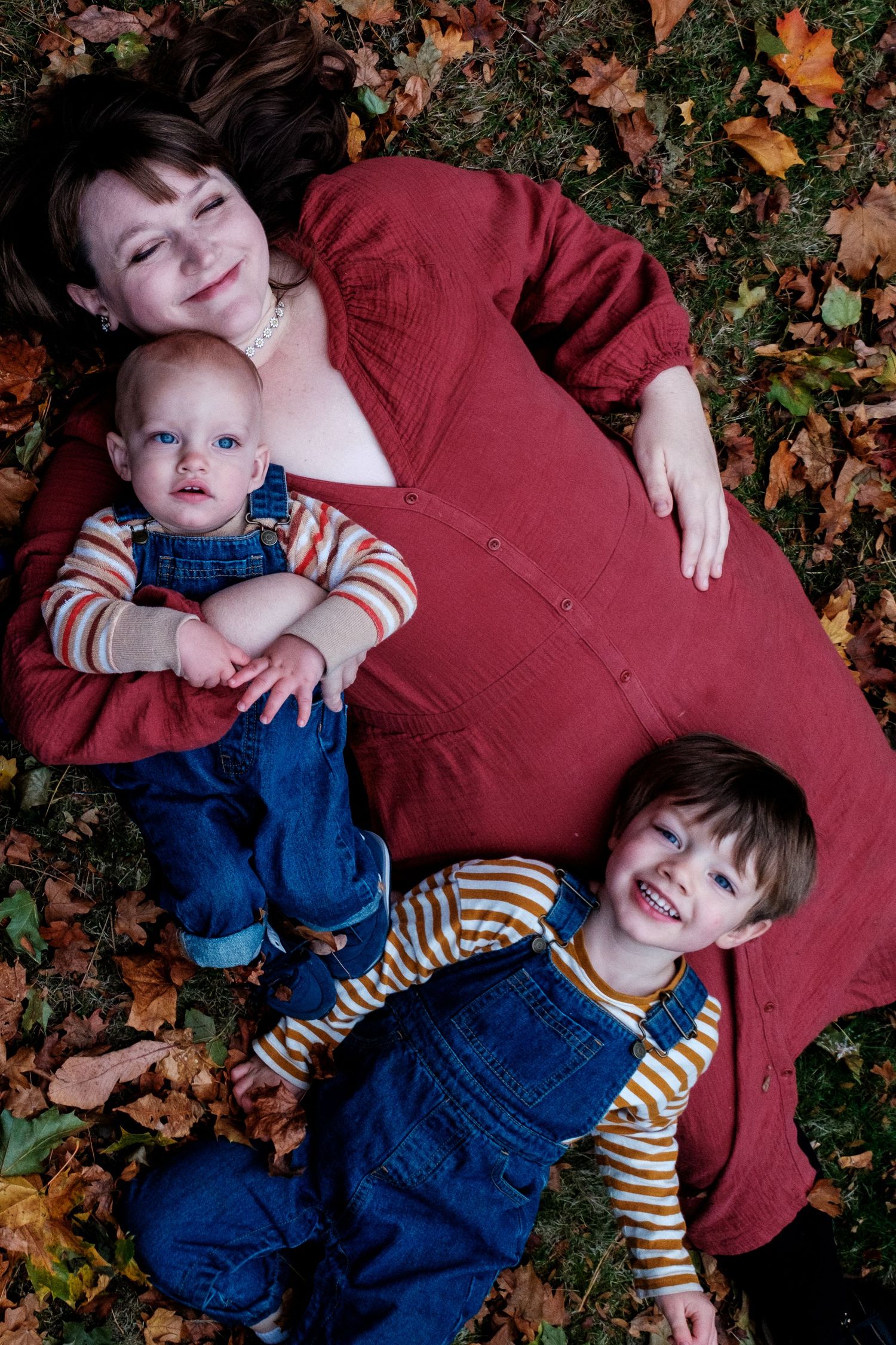 Family lying on fall leaves having fun and sharing joyful moments together.