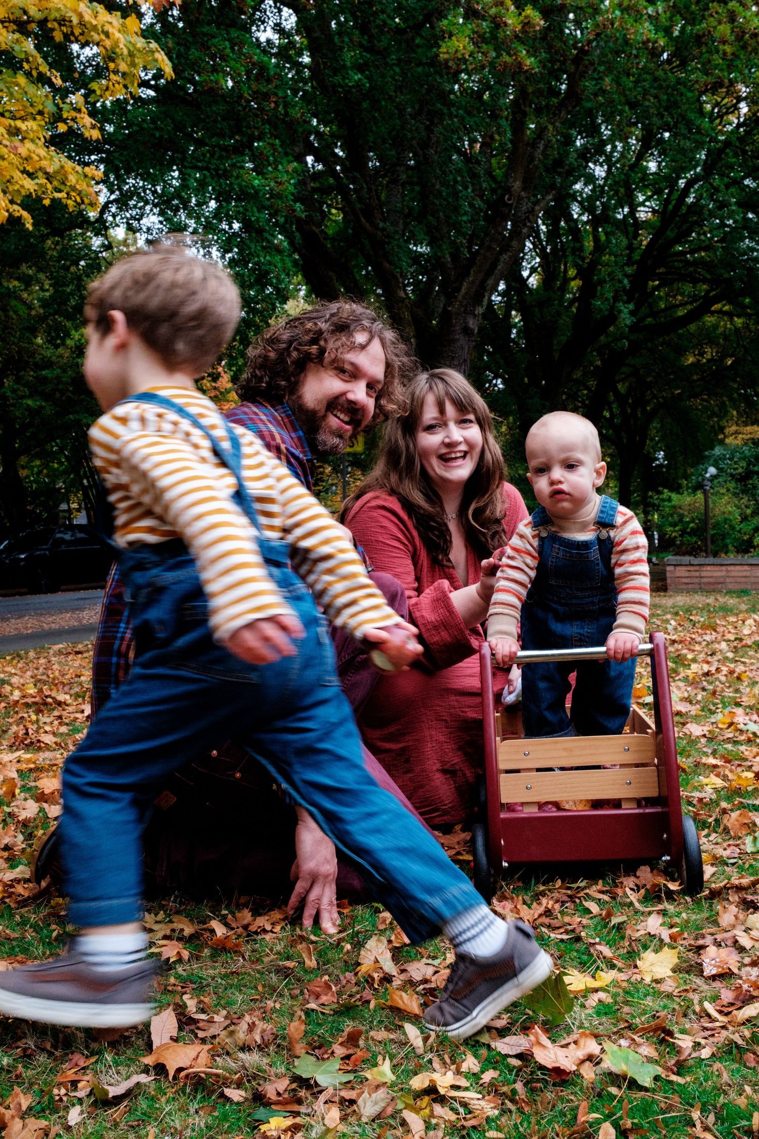 A family enjoying autumn moments together on a wooden bench surrounded by fallen leaves.