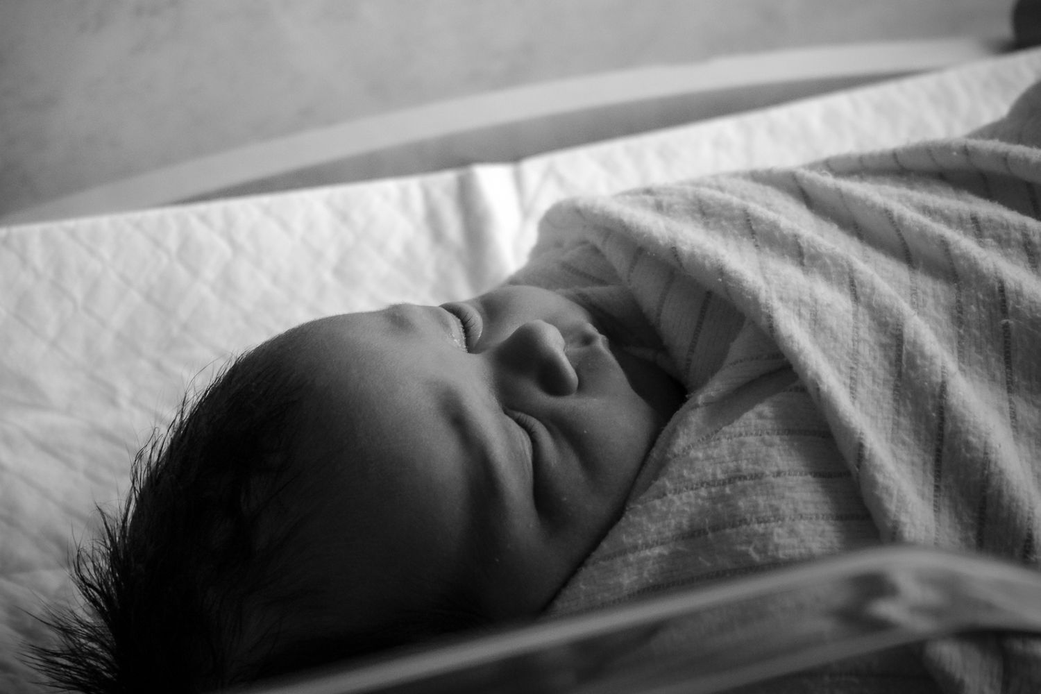 Peaceful black and white close-up of sleeping newborn baby swaddled in soft blanket. fresh 48 hospital