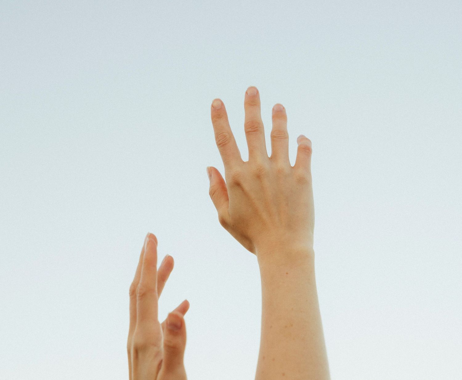 Photograph of hands reaching to sky