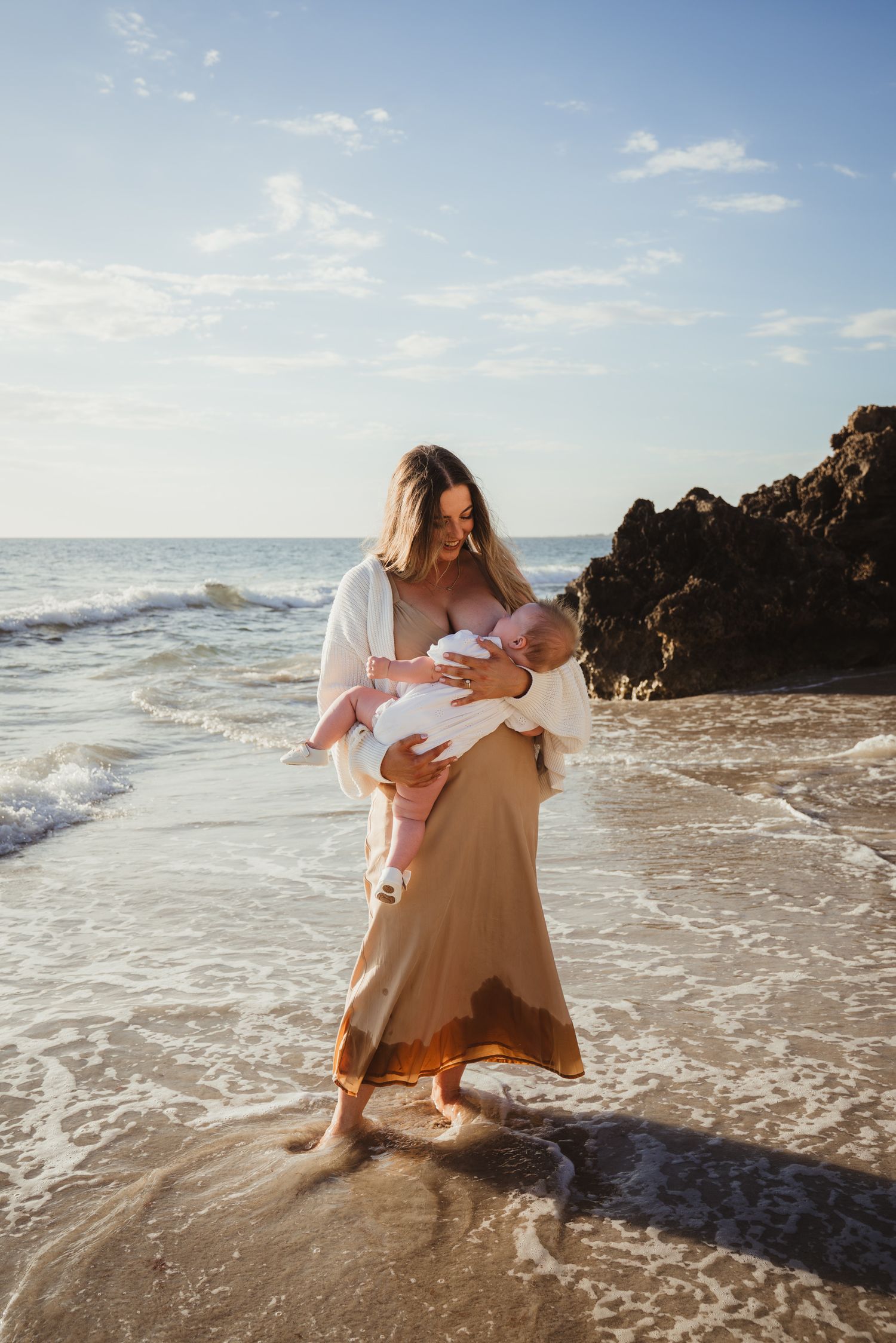 Baby breastfeeding with mother on beach