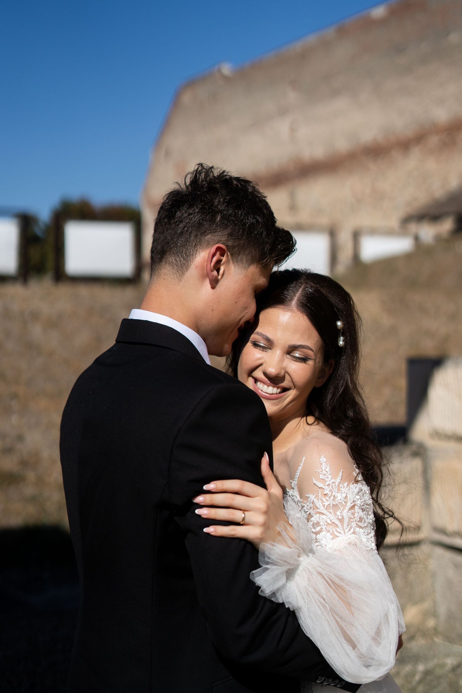 A romantic wedding moment captured against a stone wall backdrop.