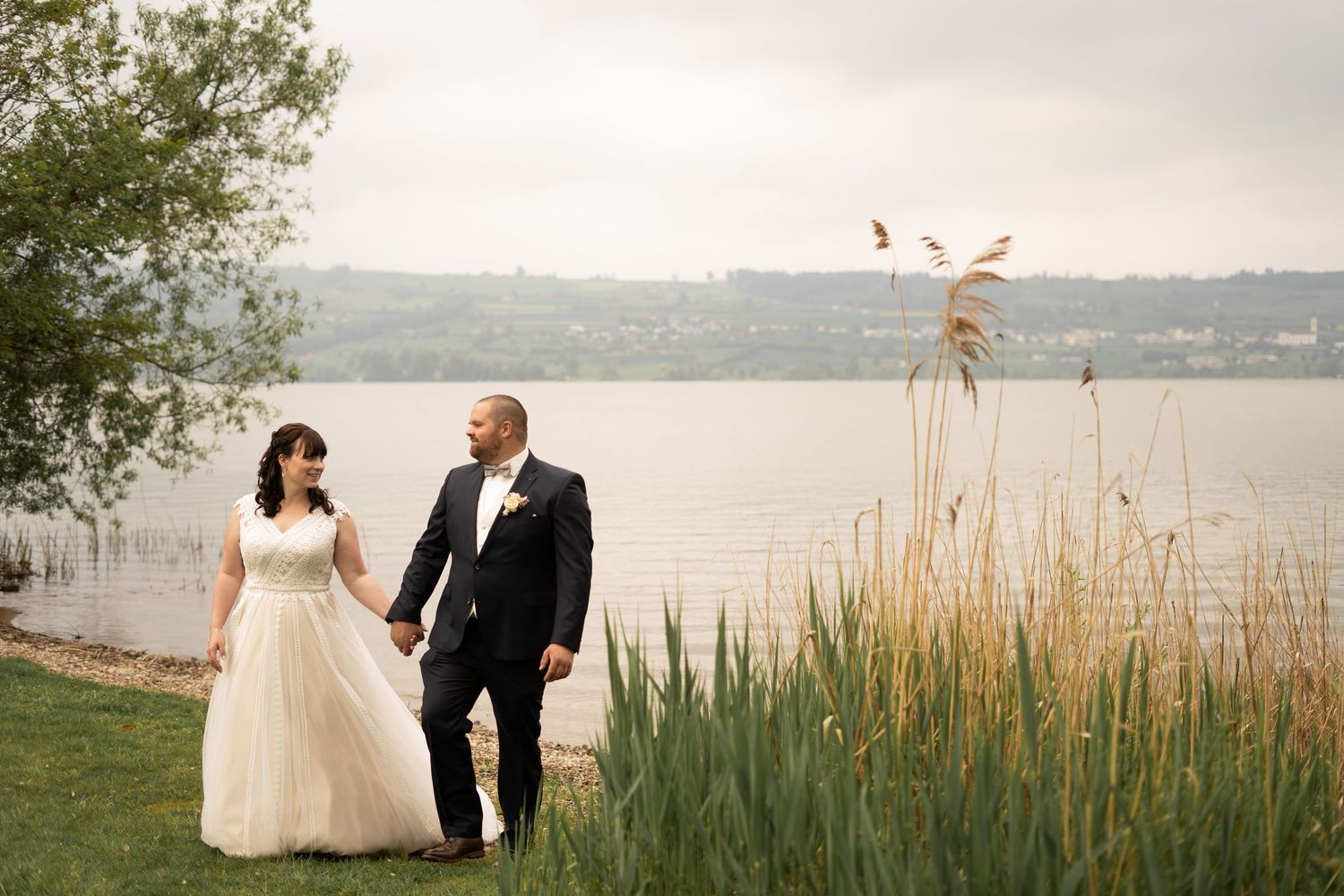 Waterfront wedding portraits with tall grass and lake views in the background.