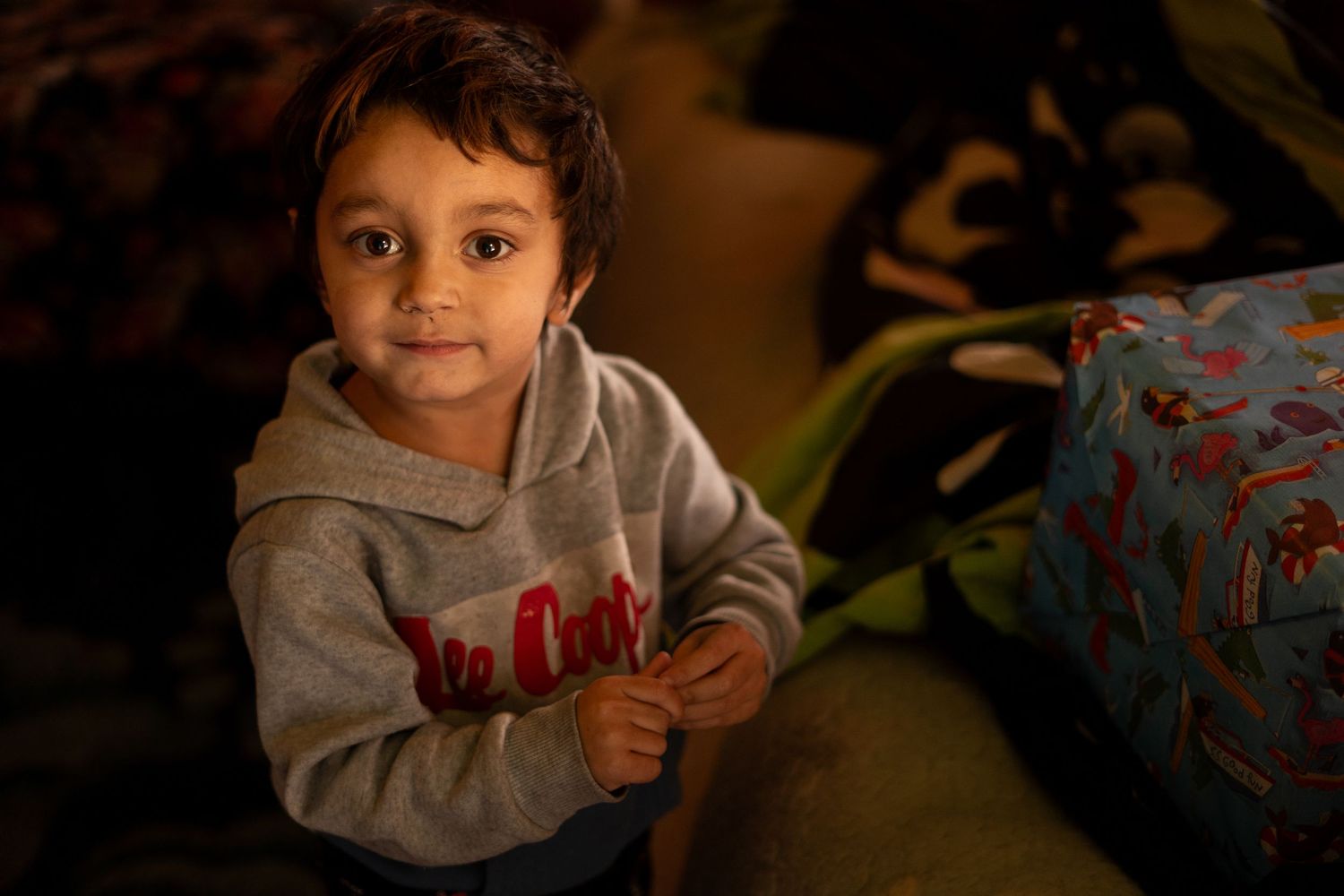 Warm indoor lighting illuminates a cozy scene with wrapped presents.